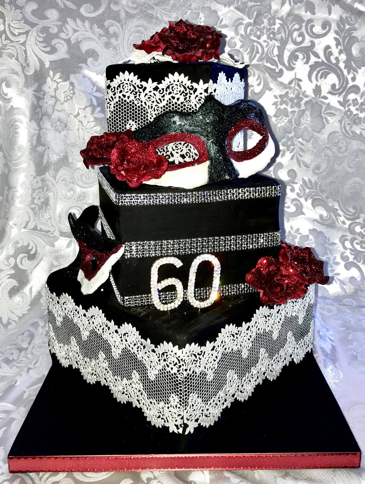 3 tier off set square theatrical birthday cake in black white and red with Masquerade masks, sugar lace and red roses.