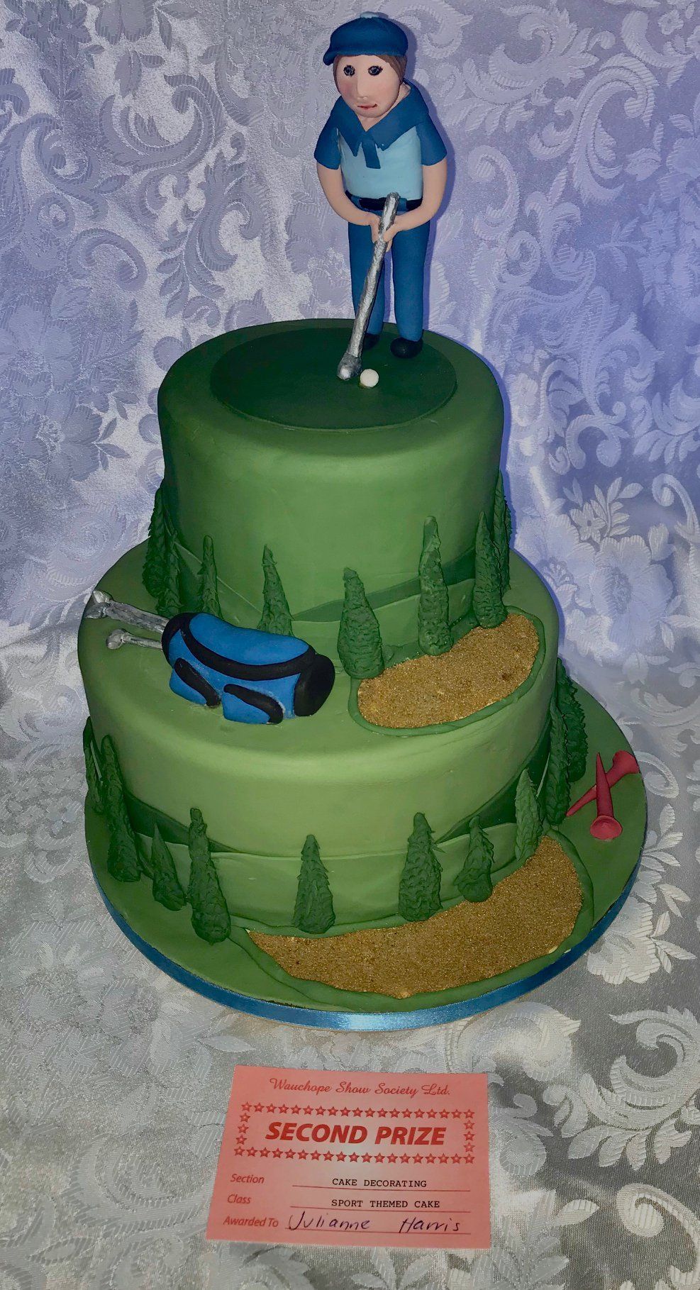 Two tier golf birthday cake with golfing range scenery, golf bag, golf tees and a golfer on top.