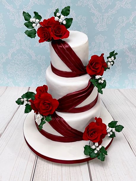 Three Tiered Wedding Cake with Red Fondant Drapes, Red Sugar Roses, Green Sugar Leaves and Sugar Babies Breath.