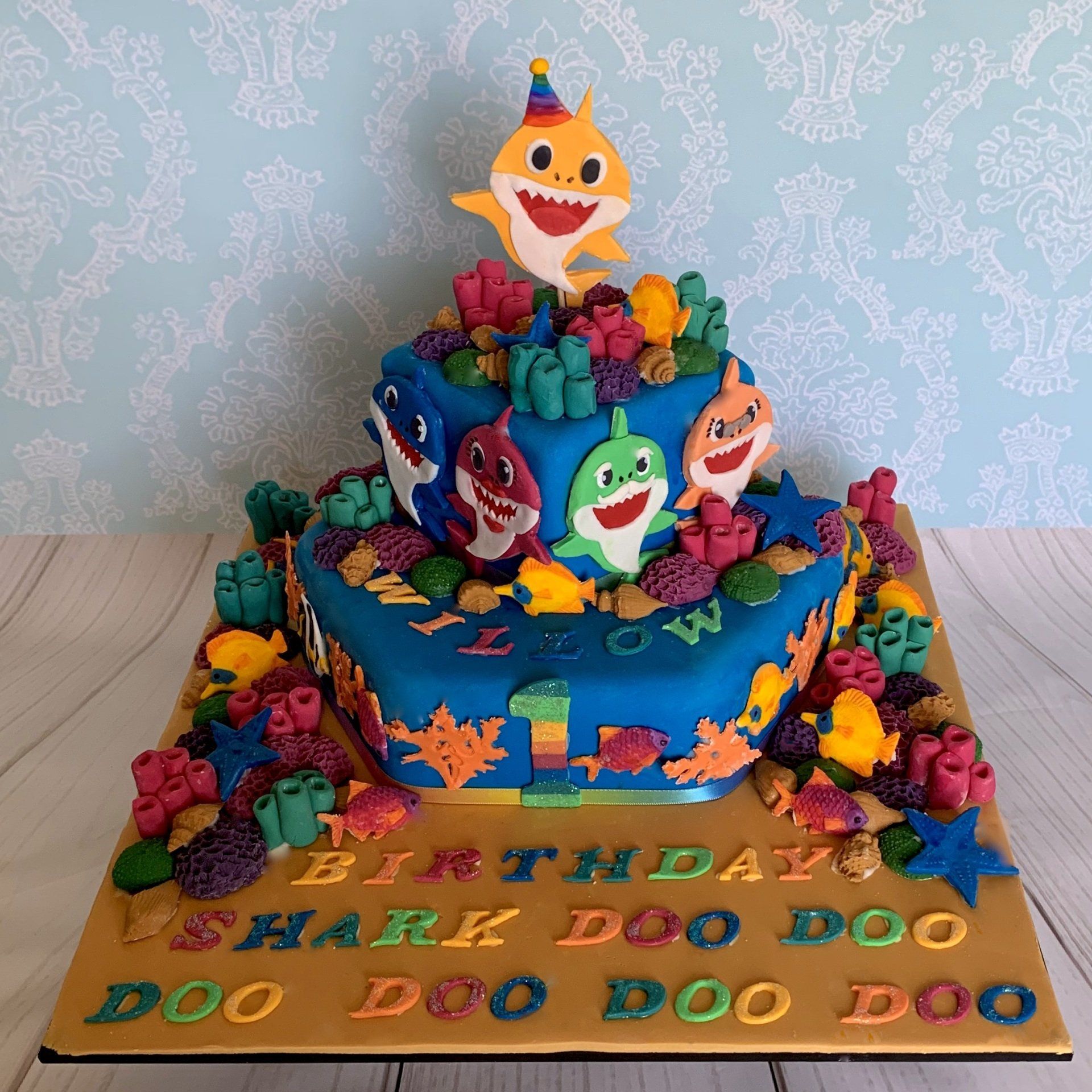 1st birthday cake. Famous hand cut fondant shark charchaters, lots of fondant coral, shells, fish and fondant sentiments. Front view