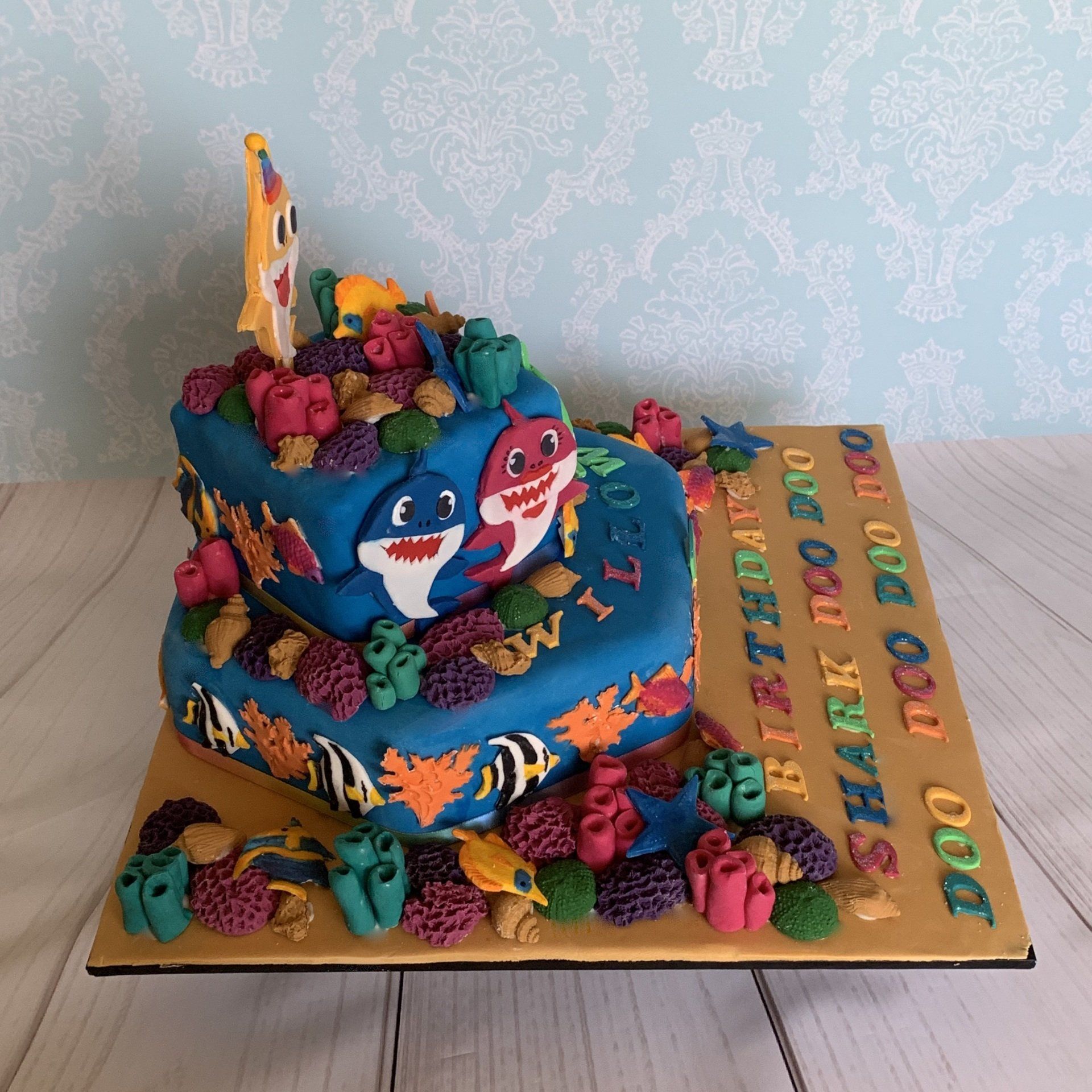 1st birthday cake. Famous hand cut fondant shark charchaters, lots of fondant coral, shells, fish and fondant sentiments. Side 2 view