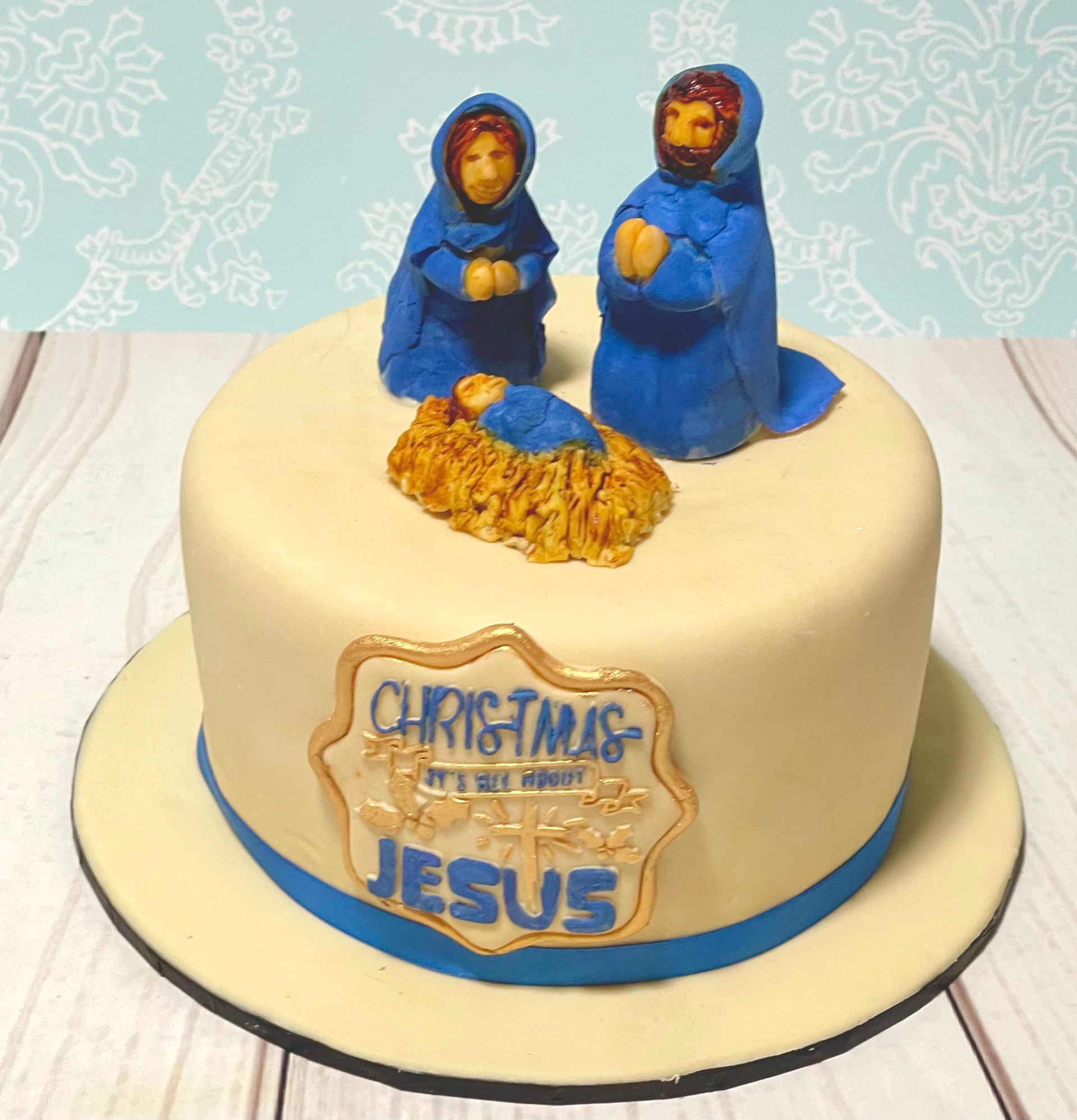 Cute little Christmas Nativity Cake with hand sculpted Mary, Joseph and Baby Jesus figurines. And a sentiment plaque saying 