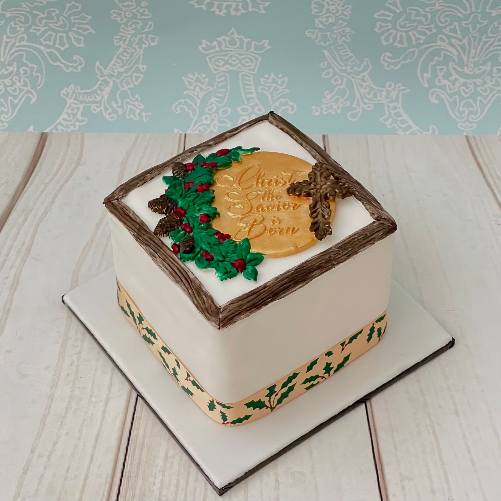Christmas Cake with fondant wood grain border, cross, holly, and Plaque that says Christ the saviour is born