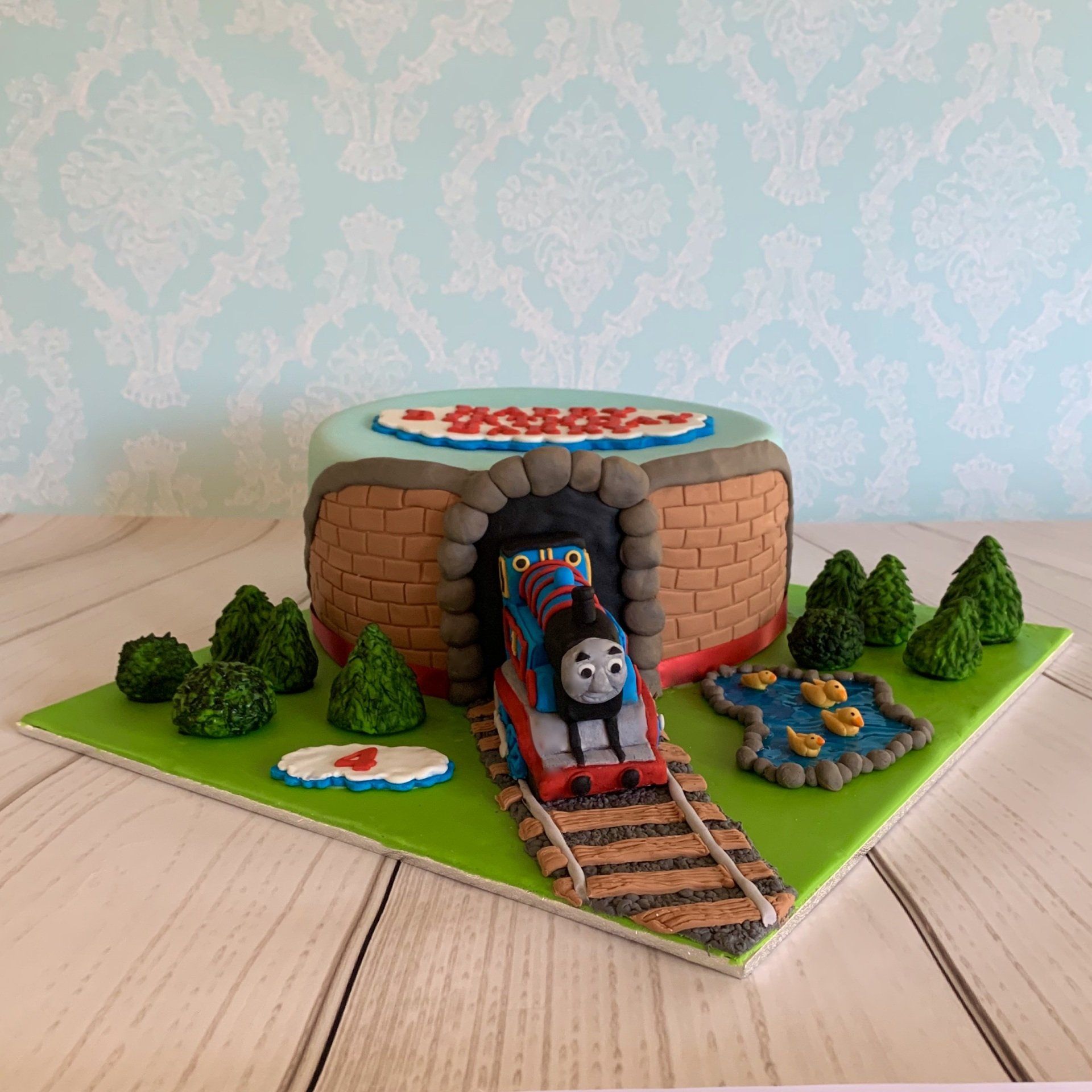 4th Boys Birthday Cake Train coming through tunnel with trees, grass and a duck pond.  Front View