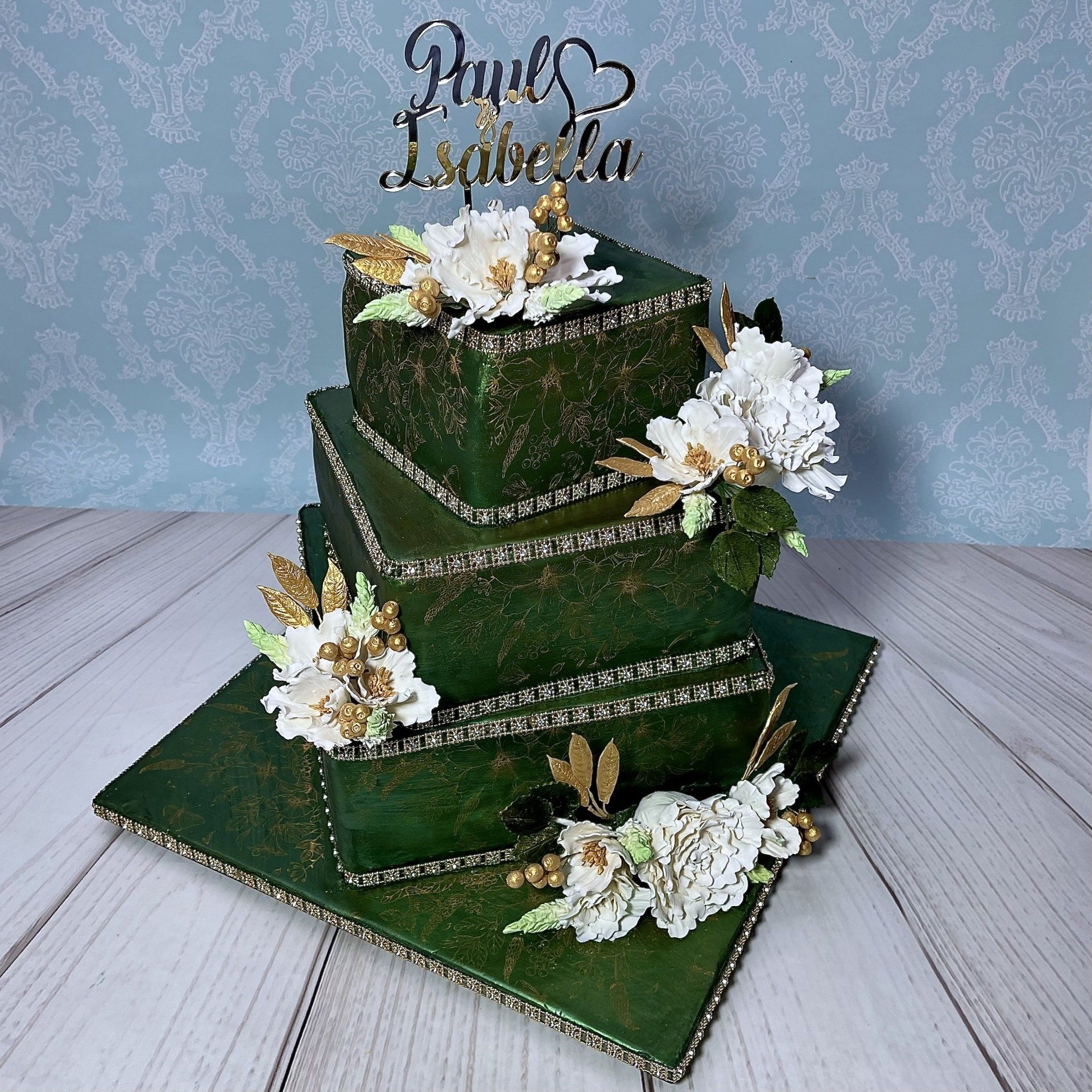 Three tier Engagement Cake, covered in green fondant with fine gold floral stencilling, personalised gold topper with customers names, and white and gold sugar flowers.