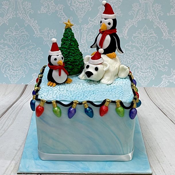 Cute Christmas cake with hand sculpted fondant Christmas Tree, Penguins, Polar Bear and Christmas Lights.