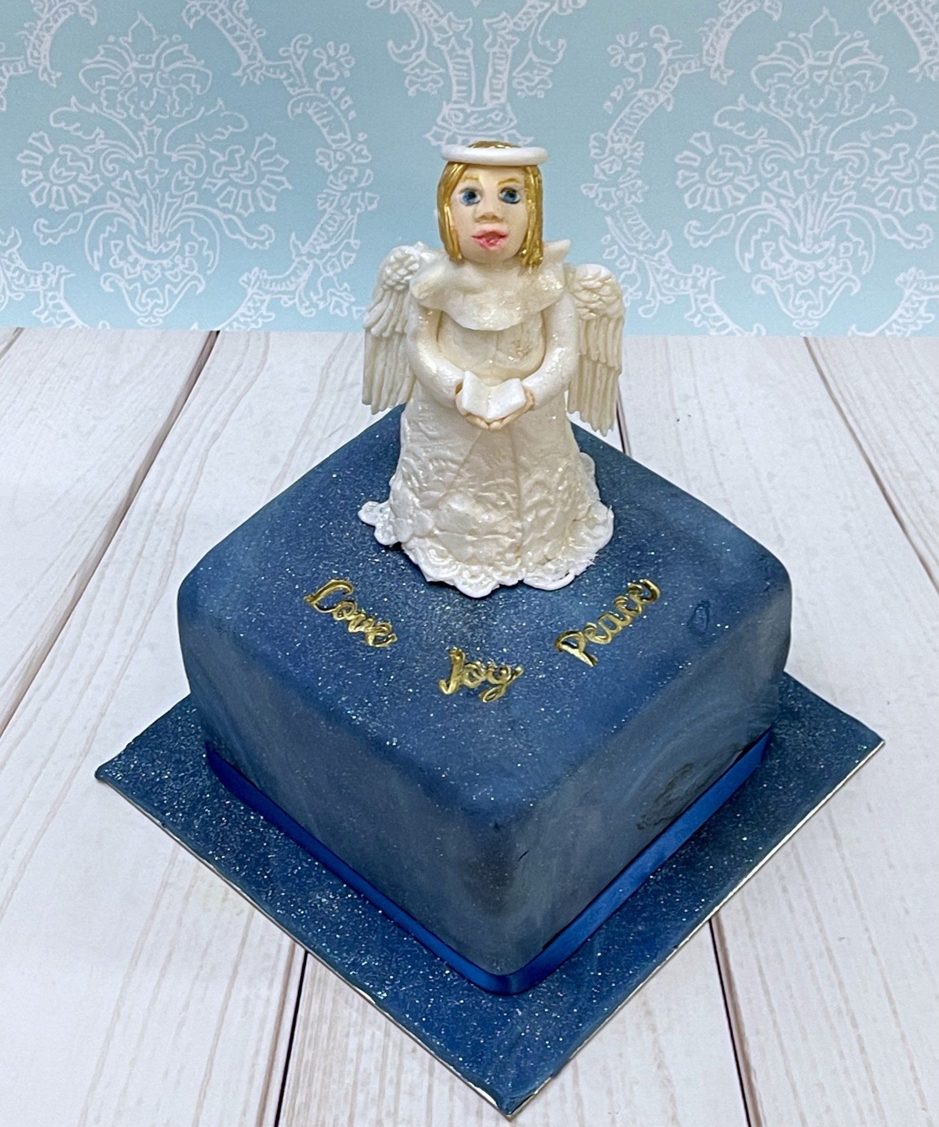 Cute Christmas cake with hand sculpted fondant choir angel  and the words peace joy love.