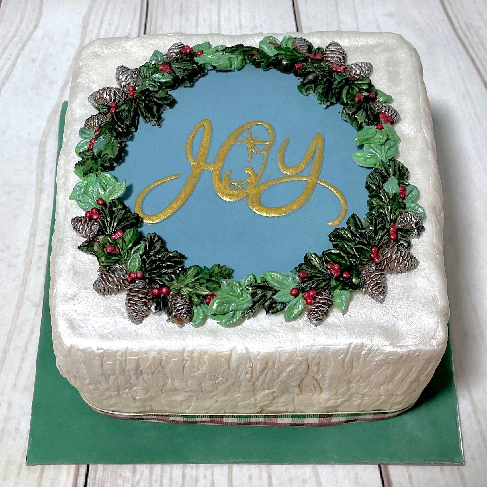 Christmas cake with a white textured fondant, Christmas Folliage and the word 