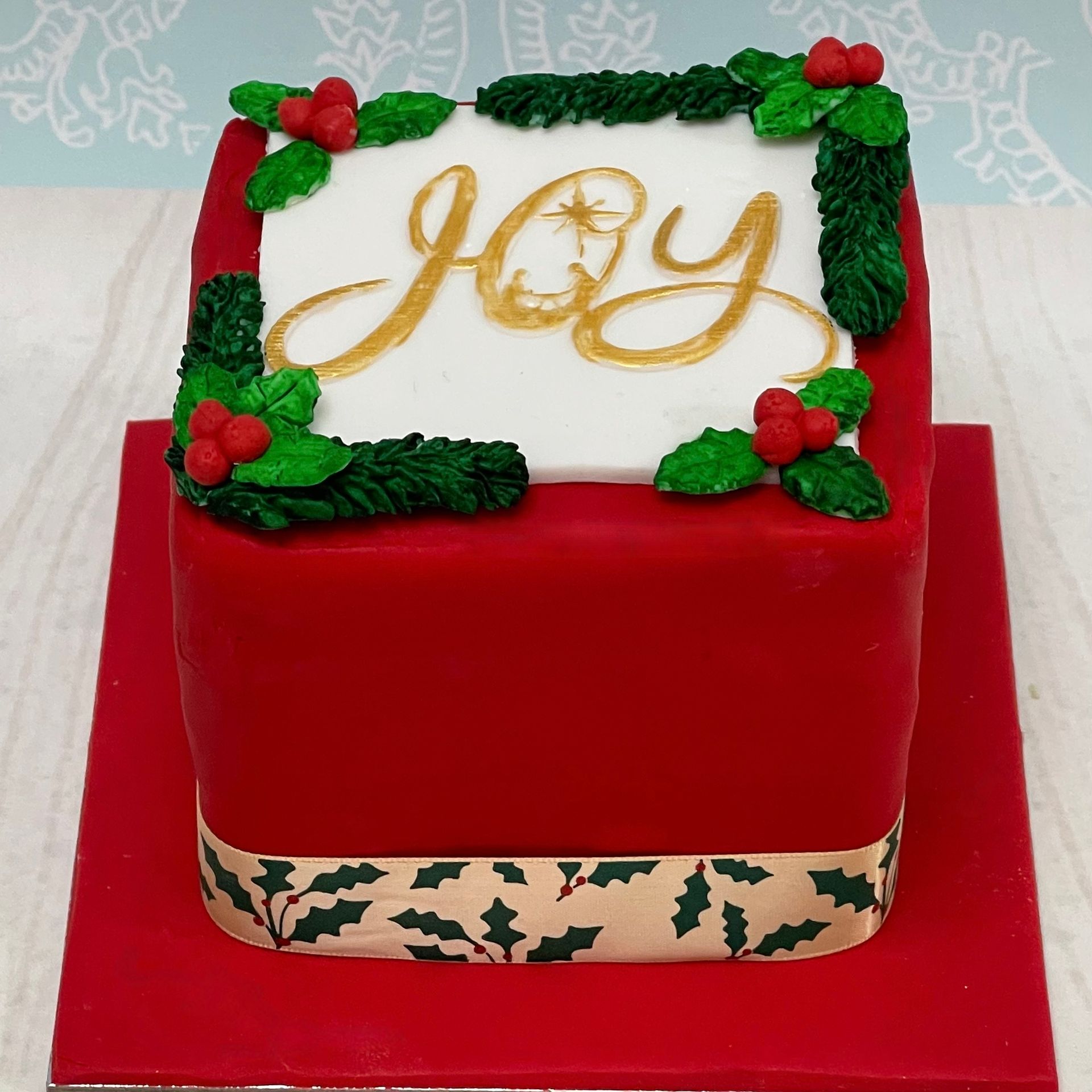 Christmas cake with a red fondant, Holly and the word 