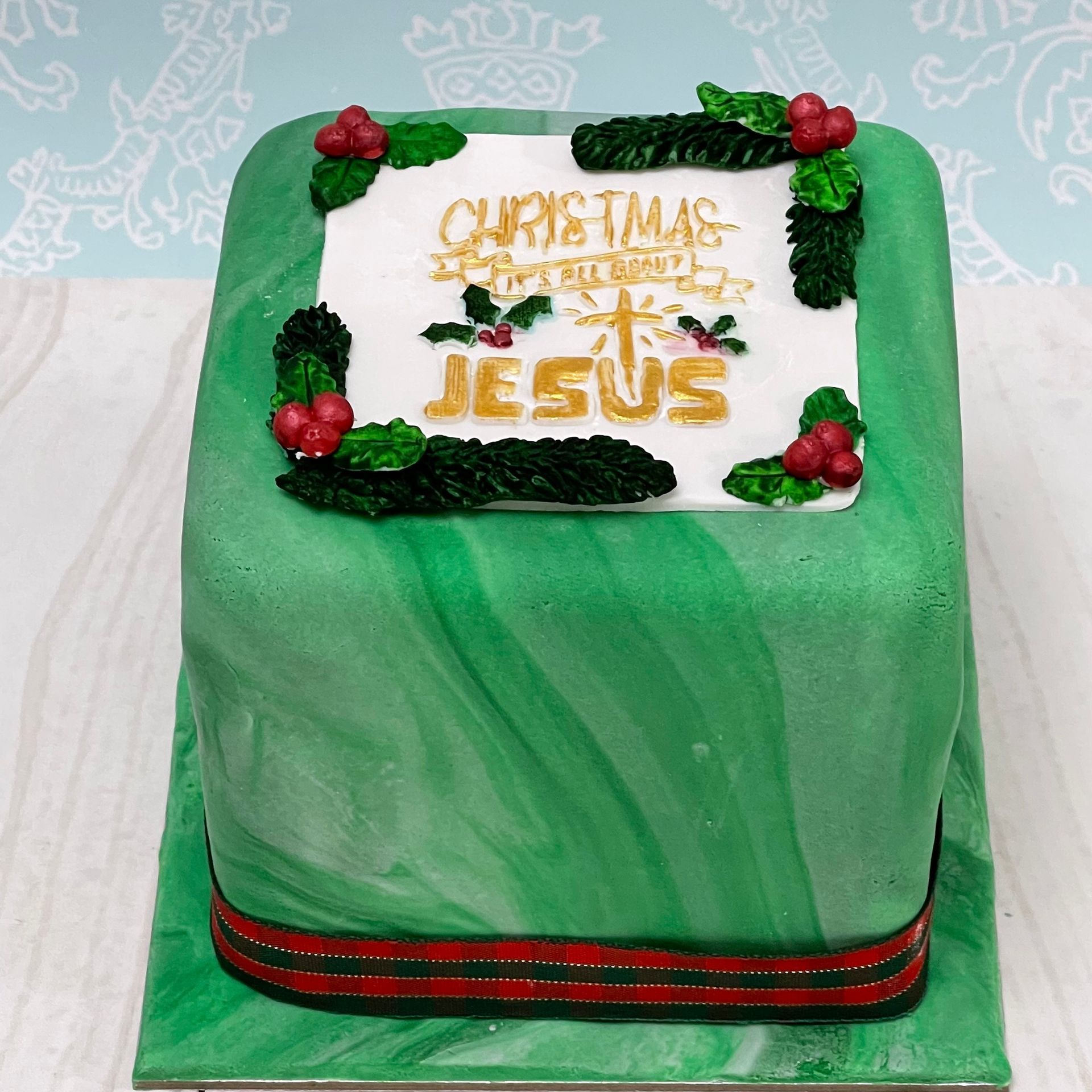 Christmas cake with a green marbled fondant, Christmas Folliage and the words 