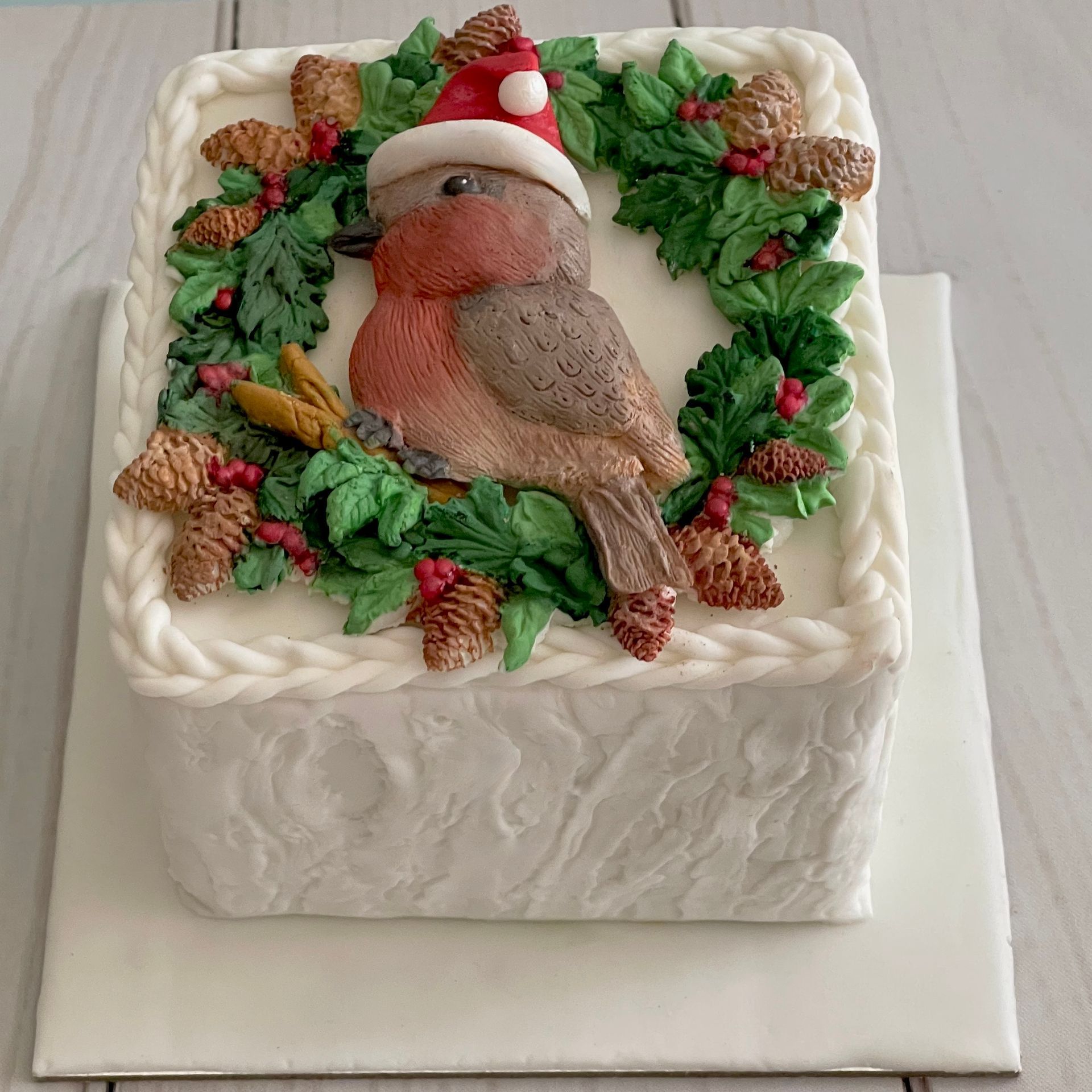 Christmas cake with White textured fondat, Christmas Foliage, and a fondant Robin with a christmas hat.