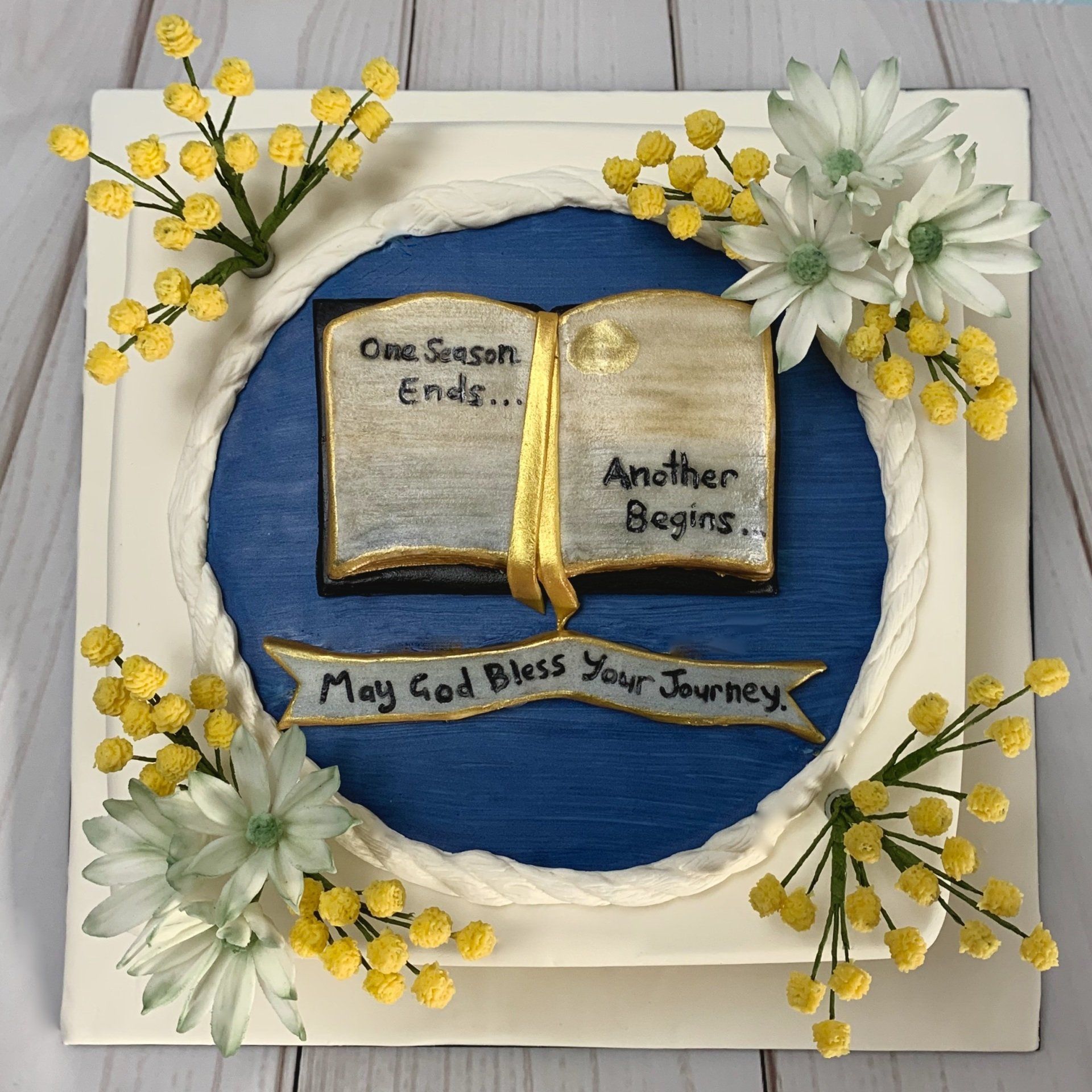 Retirement cake with hand sculpted fondant book, sugar Wattle and sugar flannel flowers