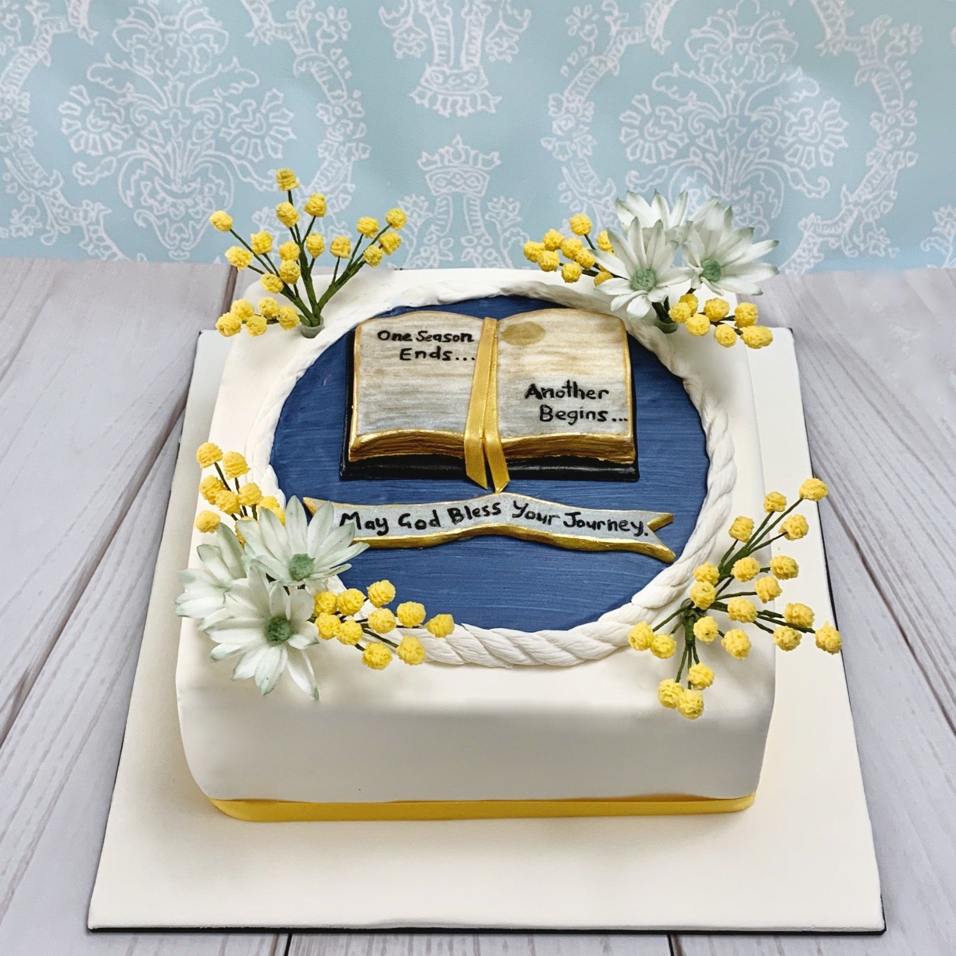 Retirement cake with hand sculpted fondant book, sugar Wattle and sugar flannel flowers