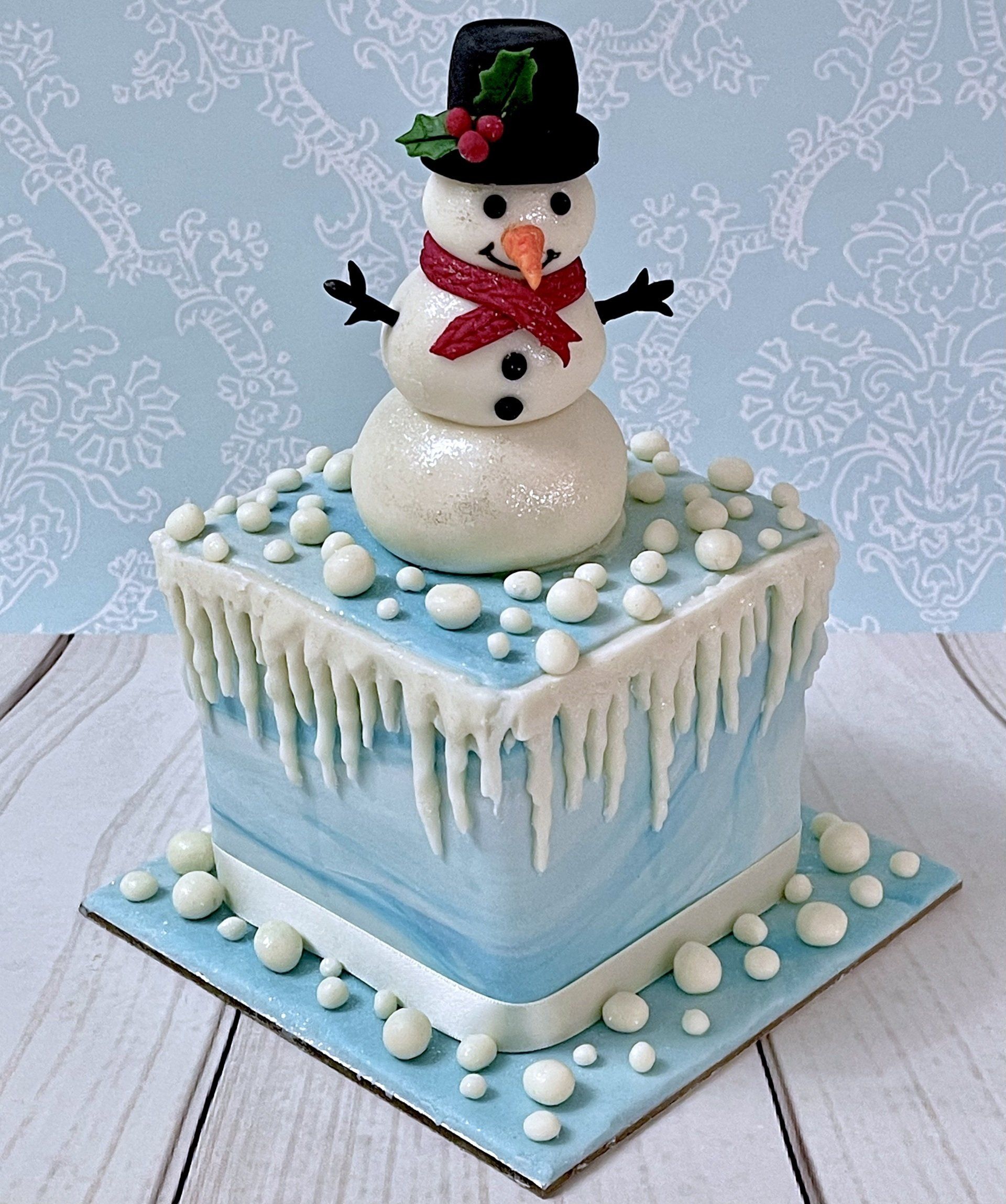 Christmas cake with hand sculpted fondant snowman, fondant icicles and fondant holly.