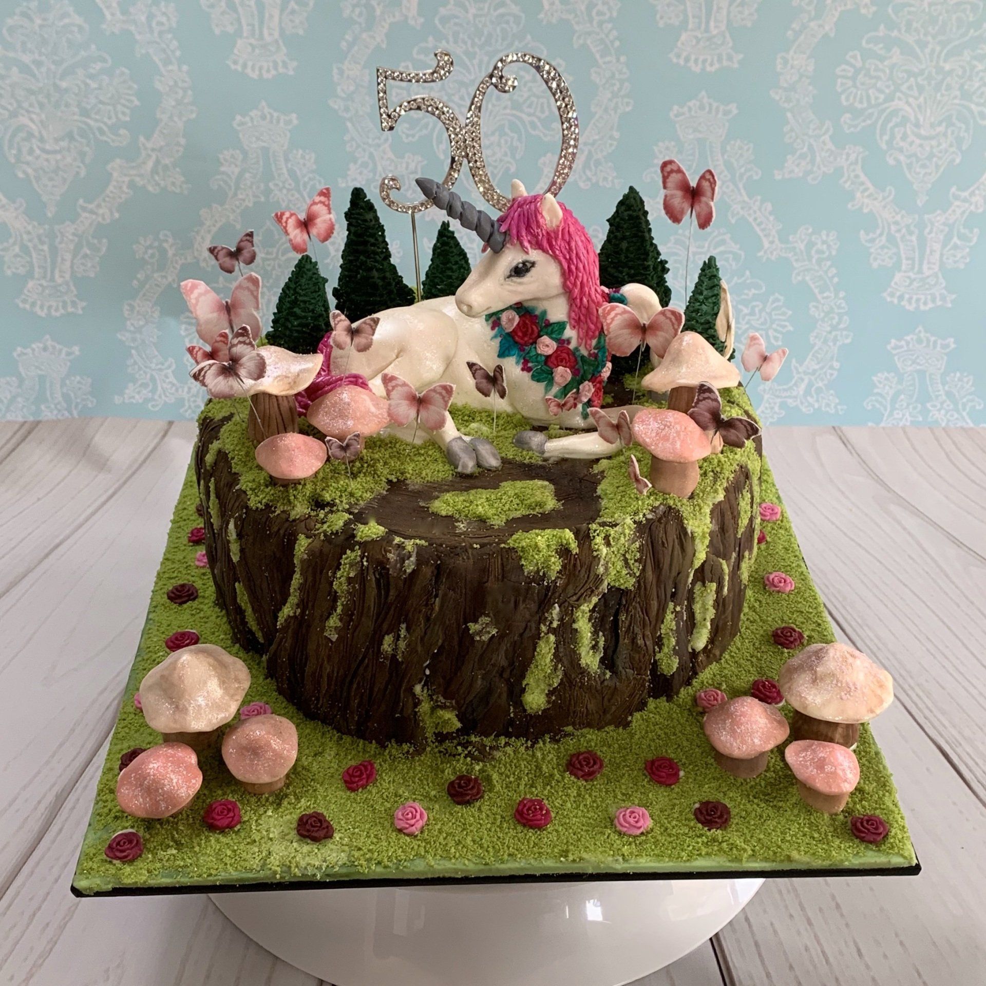 Enchanted Garden Birthday Tree stump Cake, with hand sculpted fondant unicorn, fondant trees, fondant mushrooms, wafer paper butterflies, edible moss and a diamante 50.