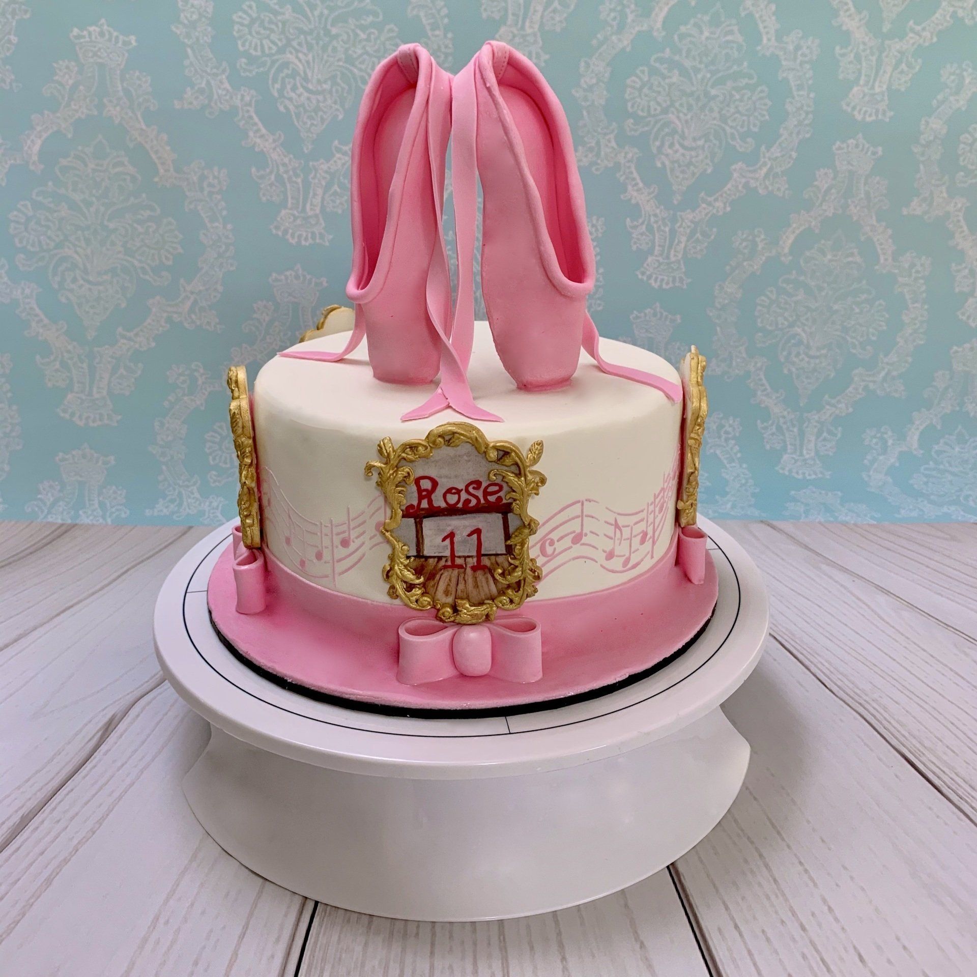 Girls Ballet Themed Cake. With Hand sculpted 3d Fondant Ballet Slippers on top, and hand painted ballerinas around the sides of the cake. Front