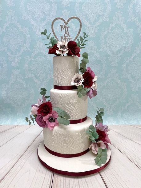 3 tiered stenciled Wedding Cake with burgundy and lilac sugar roses, sugar eucalyptus leaves, white and lilac sugar anemone flowers, white and lavender alstroemeria lilies and a diamanté heart Mr & Mrs topper