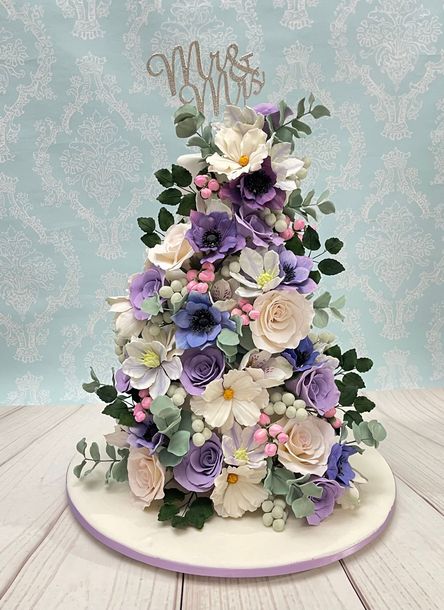 Gorgeous Wedding Cake Port Macquarie. White fondant, Mauve Ribbon Trim, Diamanté Mr & Mrs Topper and Cascading White and shades of Mauve Sugar Flowers.