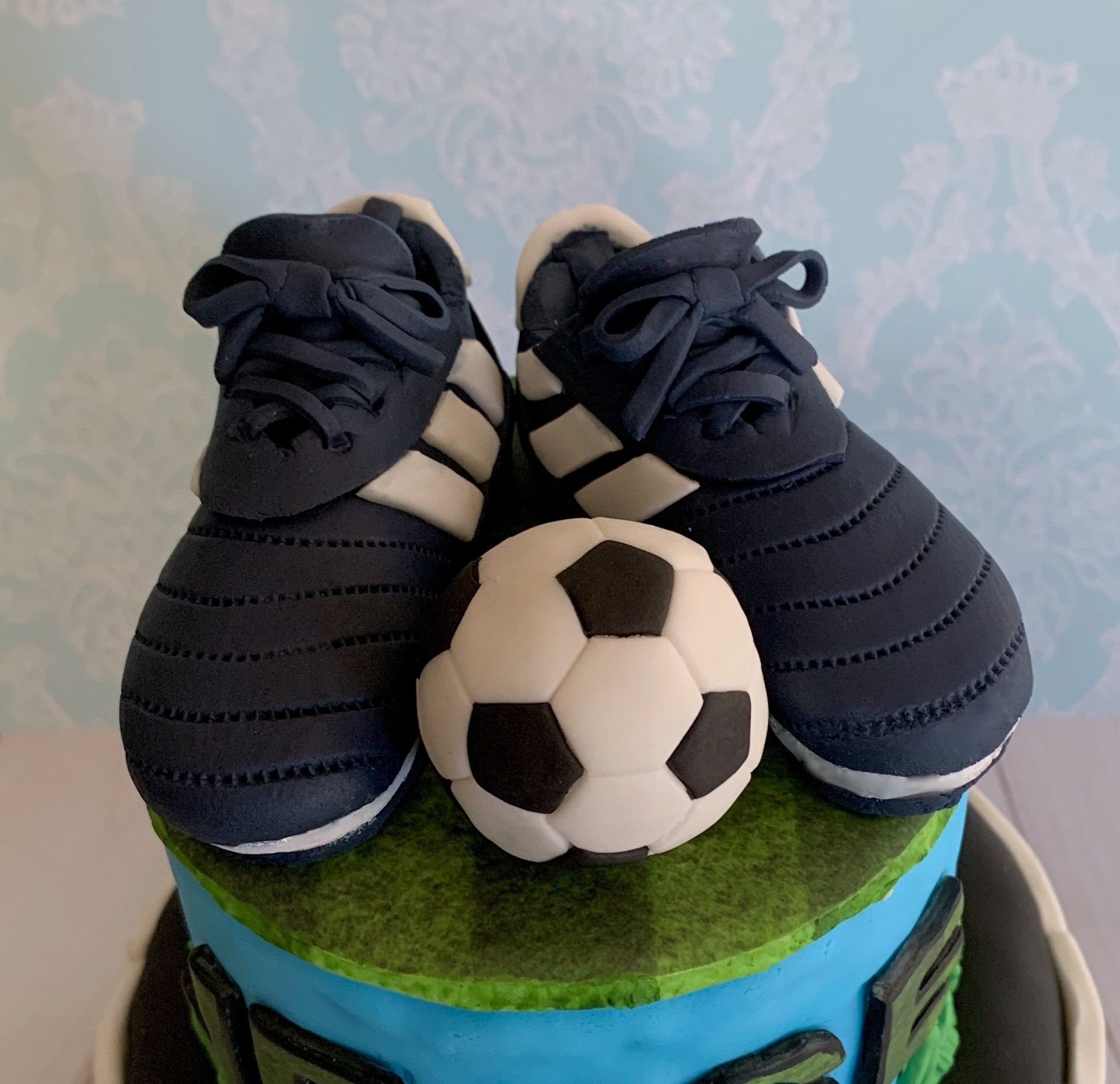 Hand sculpted soccer shoes and soccer ball fondant topper.