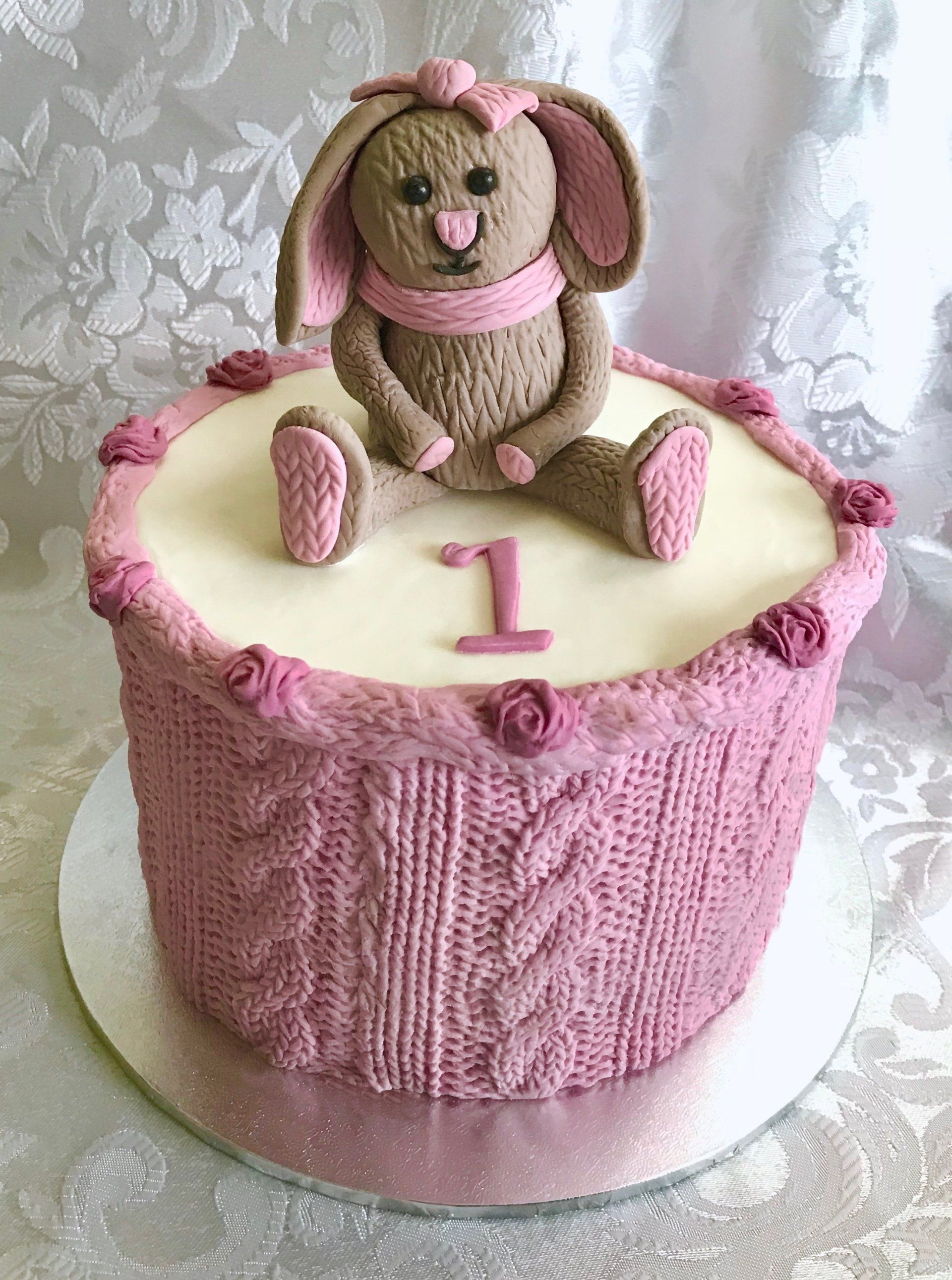 Girls 1st Birthday Cake. Cute knitted sugar rabbit with pink knitted fondant sides and pink roses