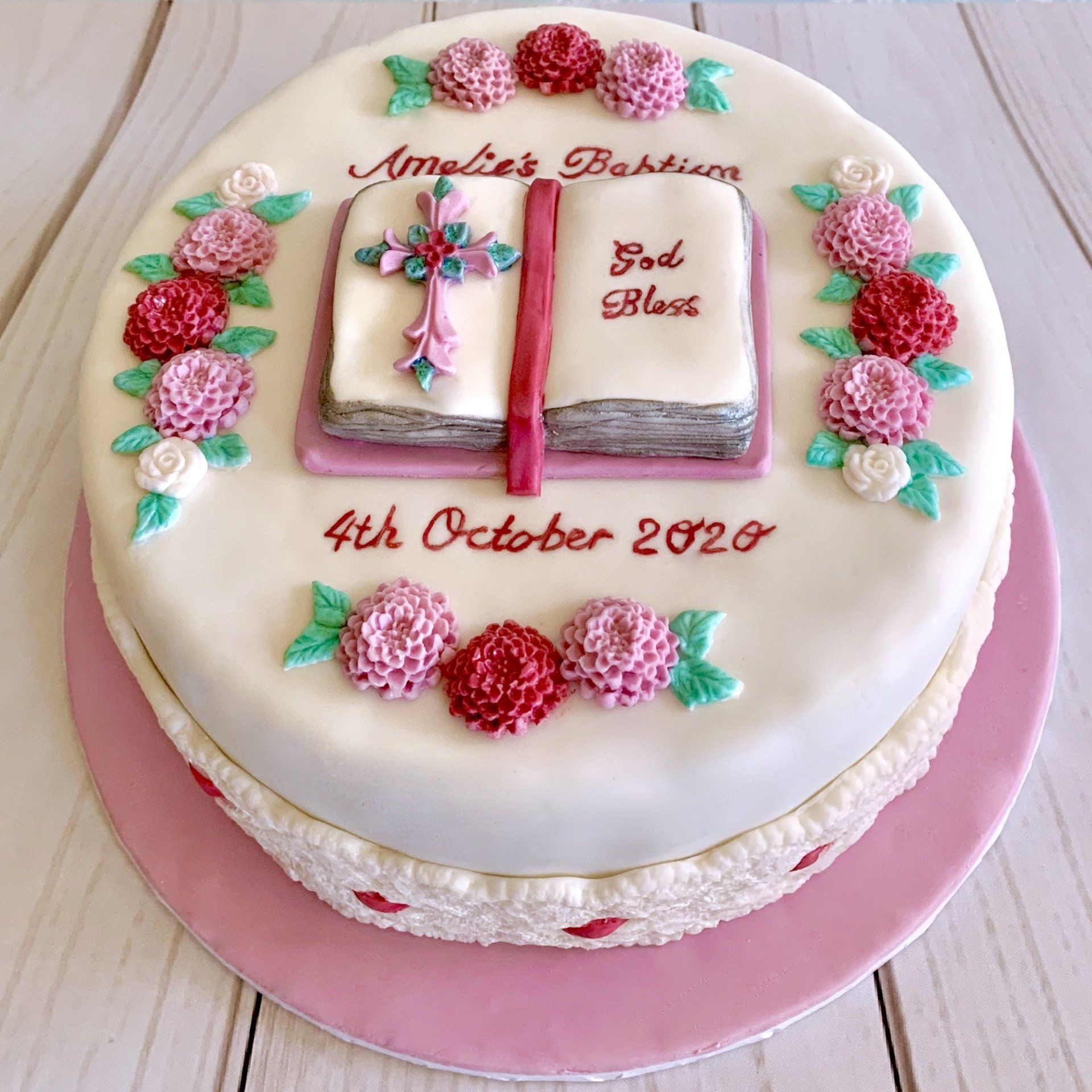 Christening, Baptisim Cake. With white fondant, Pink sugar flowers, pink hand painted writting. and a Handscuplted fondant bible with cross and details in white and pink.