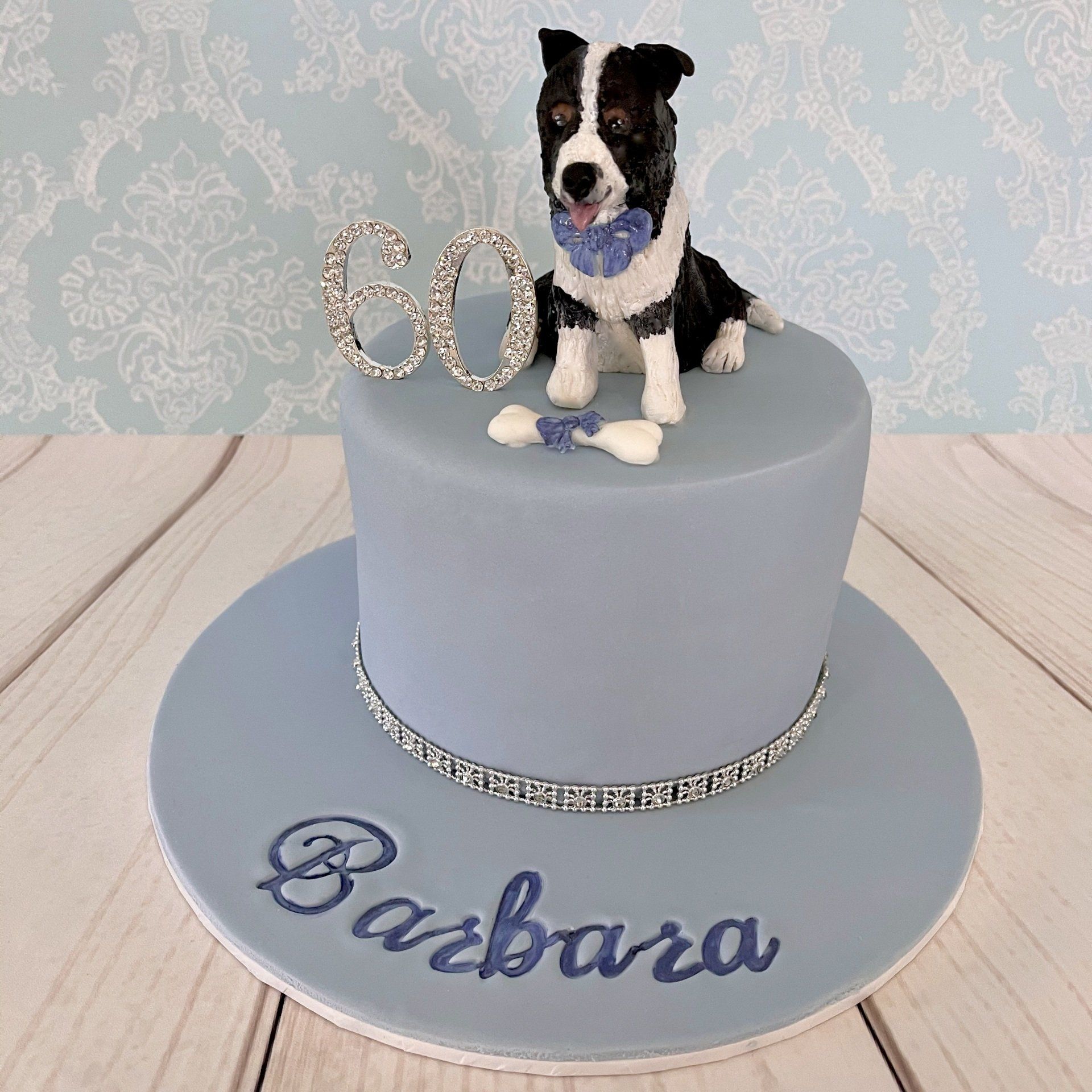 Gorgeous Birthday Cake with light blue fondant, diamanté trim, diamanté 60 and a very cute hand sculpted fondant border collie dog with blue bow on top.