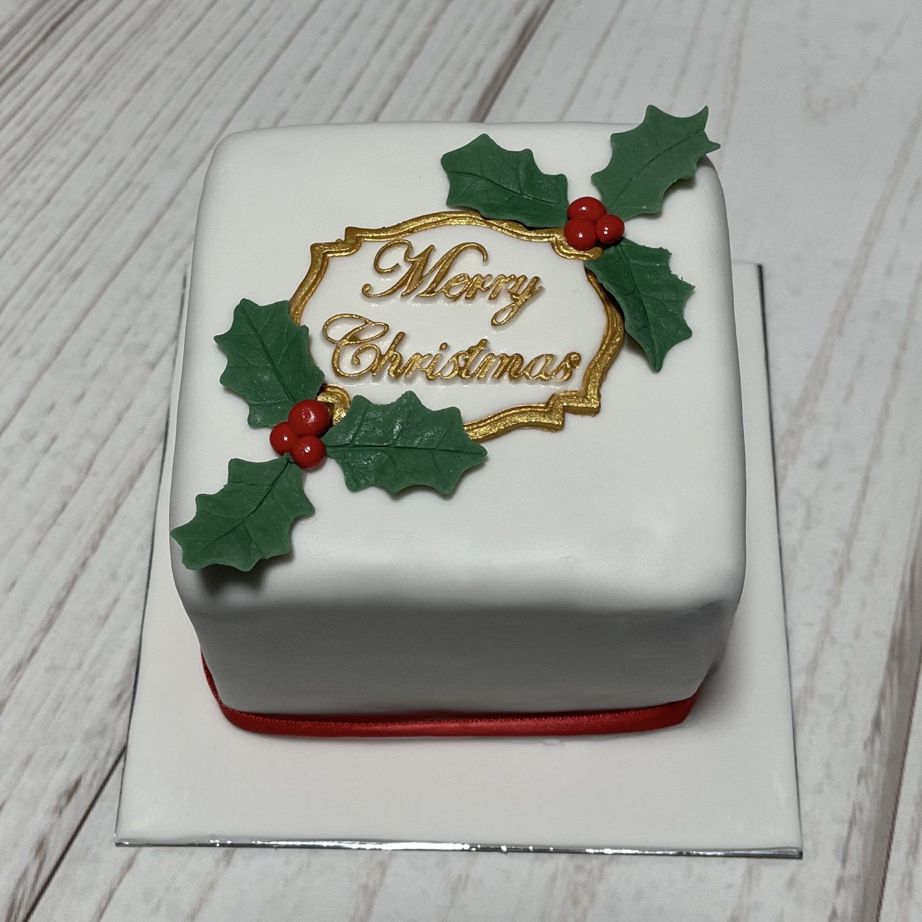 Christmas cake with Fondant Holly and the words Mery Christmas