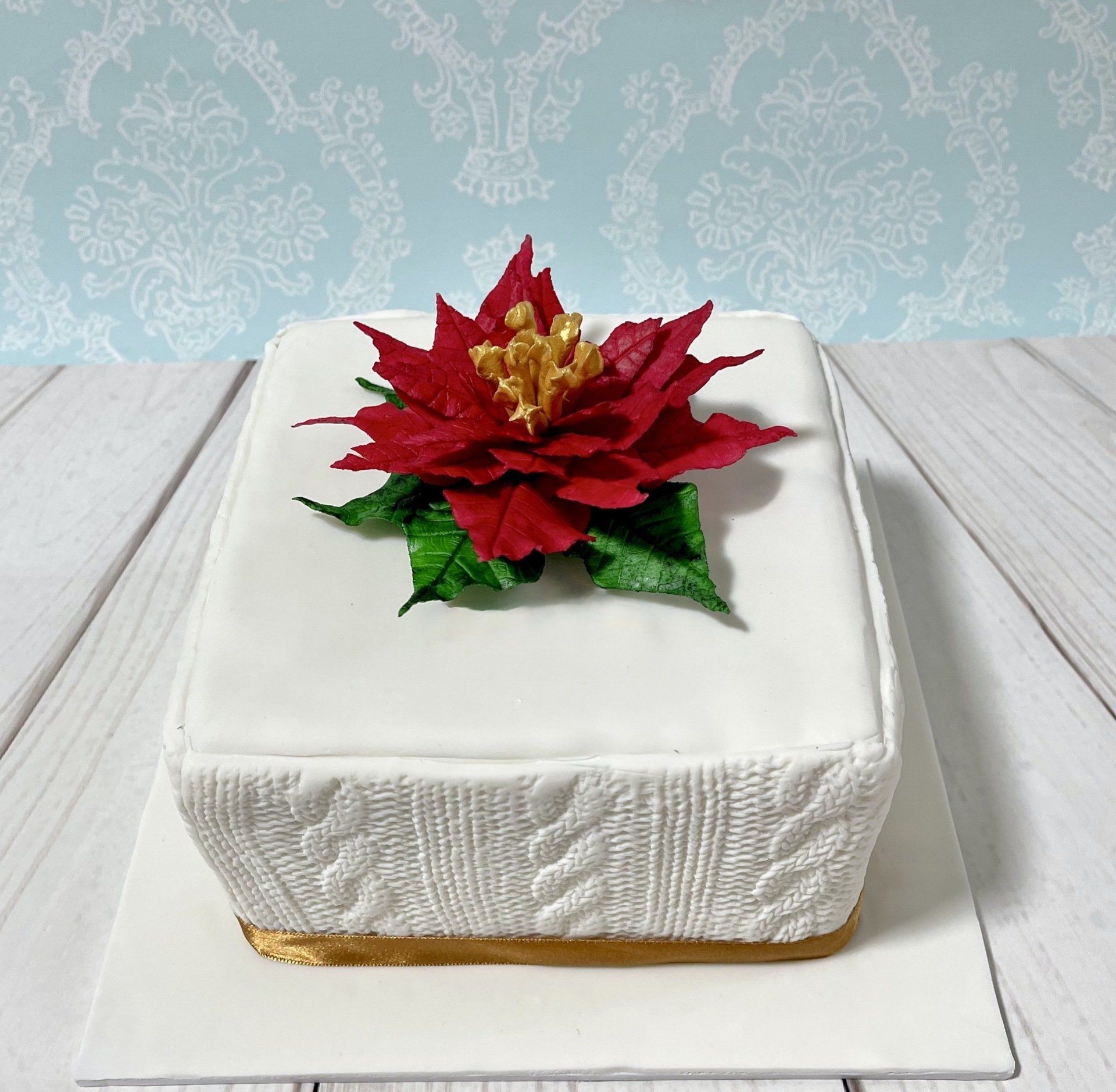 Christmas cake with white fondant and a sugar poinsettia