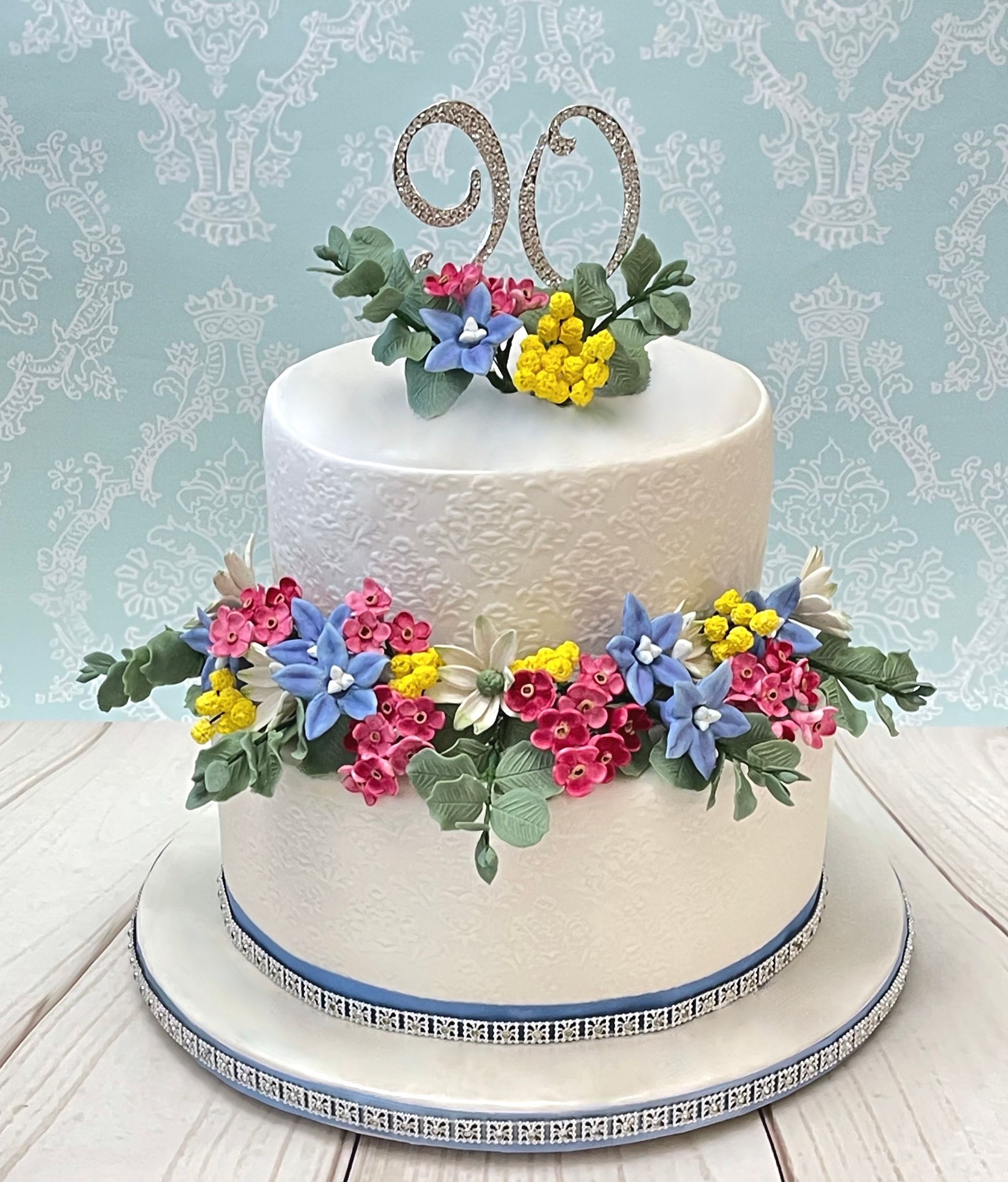 White embossed 2 tiered cake with Australian Sugar Flowers, Diamante trim and Diamanter 90