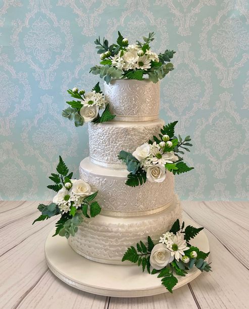 4 tiered wedding cake Port Macquarie with pearl white texured tiers and lots of white and green sugar flowers and leaves.