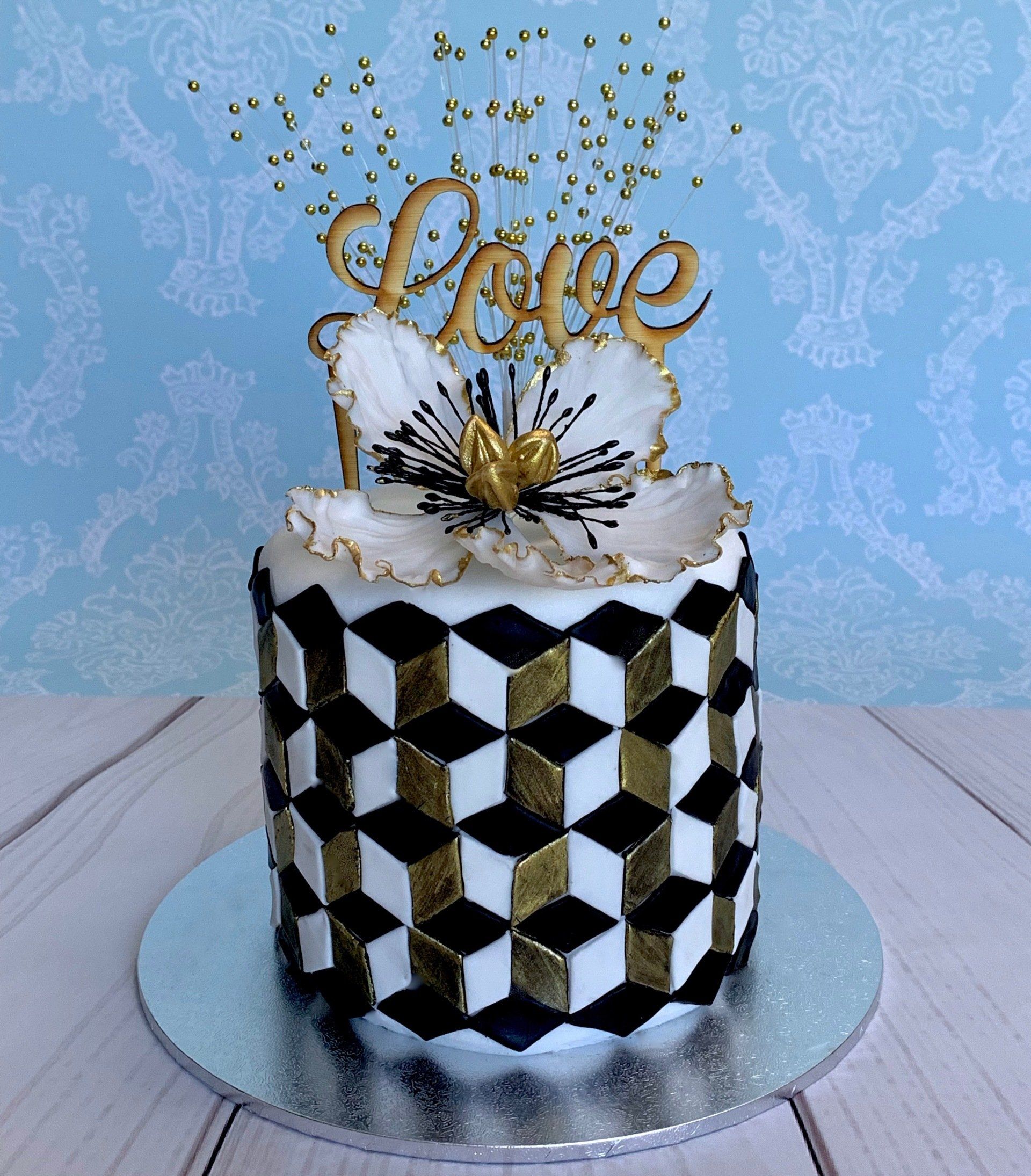 Optical illusions cake in black gold and white. Wooden topper saying love and a beautiful fantasy sugar flower.