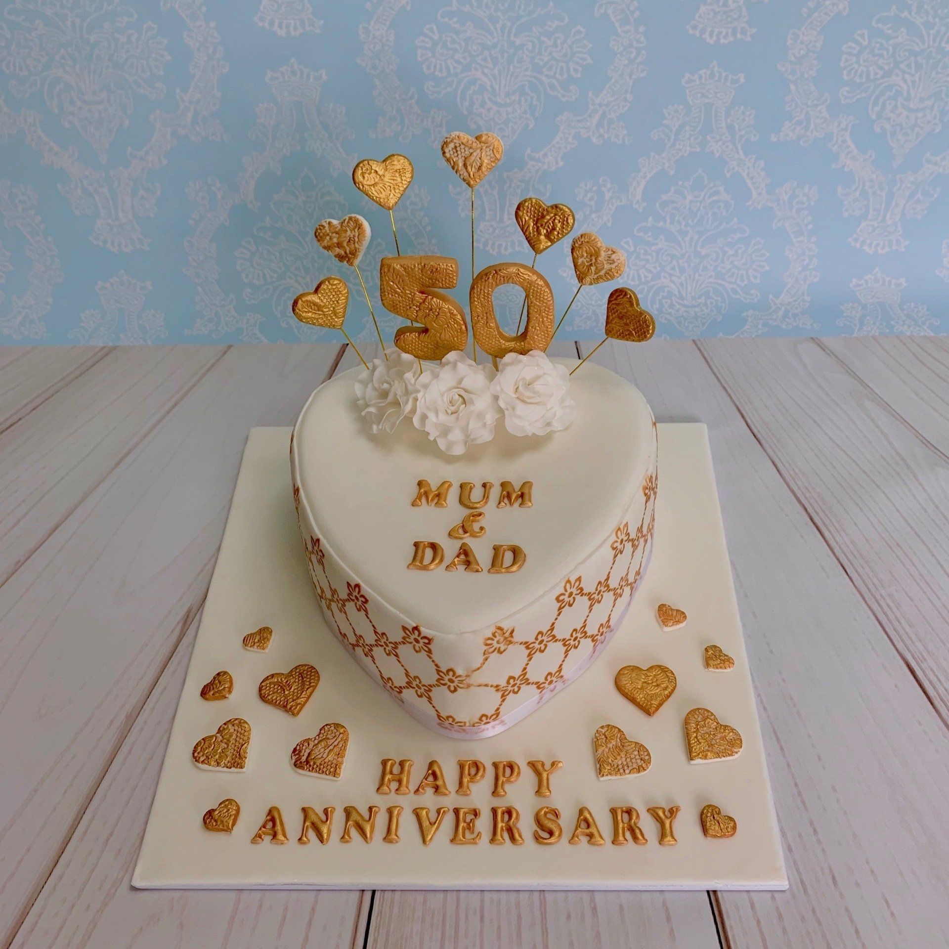 50th golden wedding anniversary cake. Heart shaped white fondant with gold heart sprays, gold writting and white roses