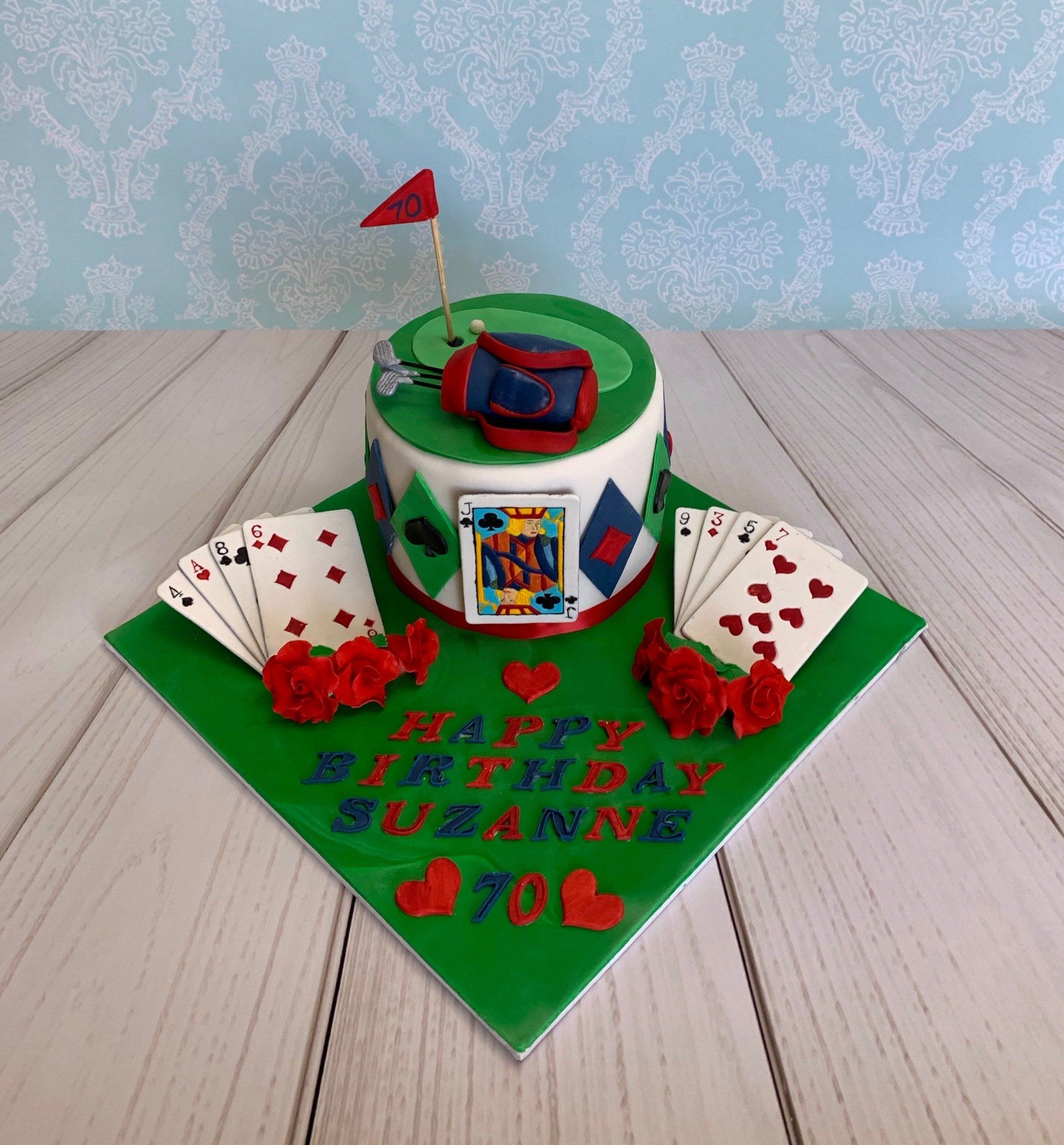 Ladies 70th golf and bridge card game cake with golf green, gold flag, golf ball and golf bag on top. Playing cards roses and writing on the cake board.