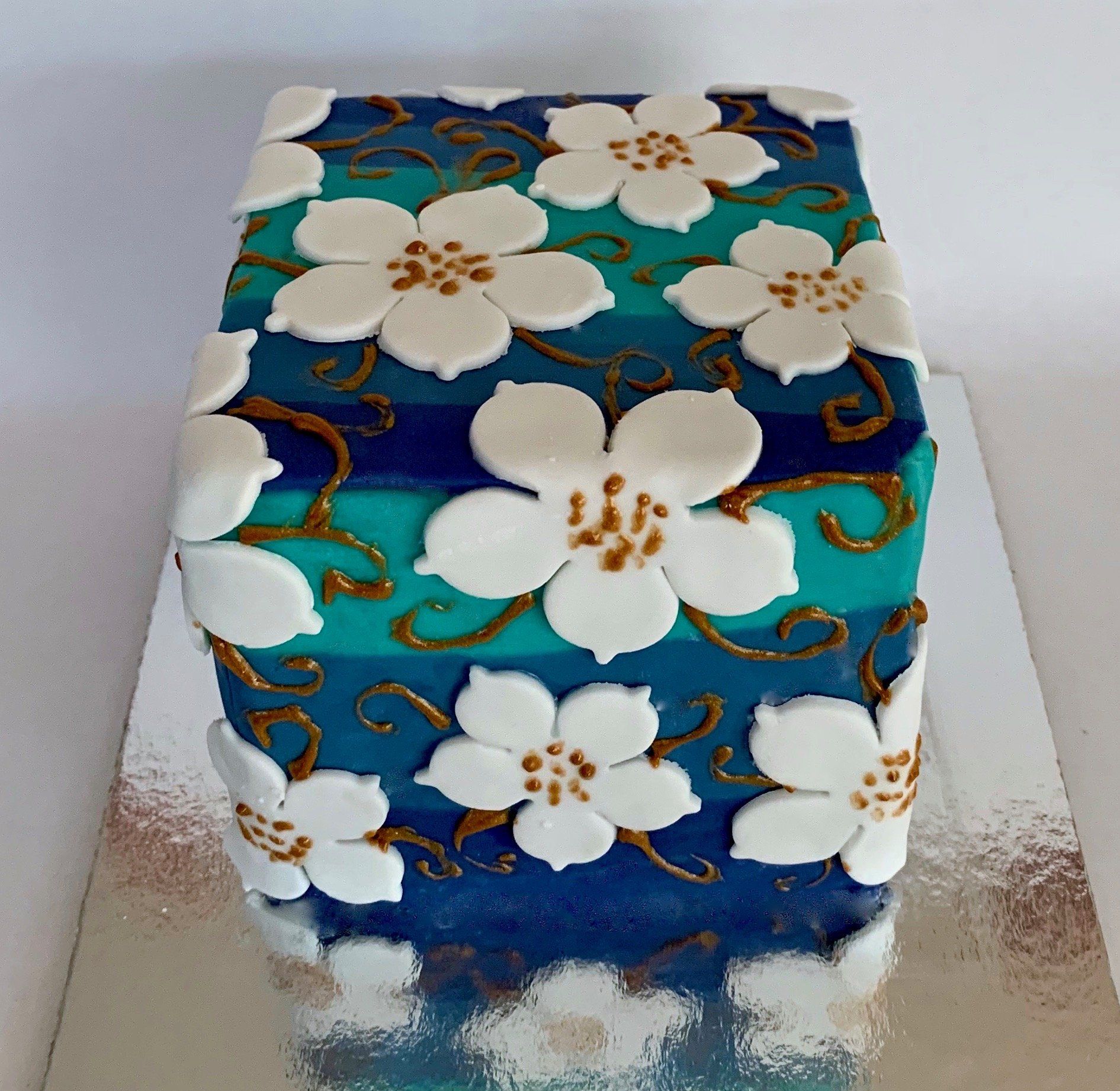 Mini Cake in ombre blue and teal, white cut out flowrs and painted gold swirls