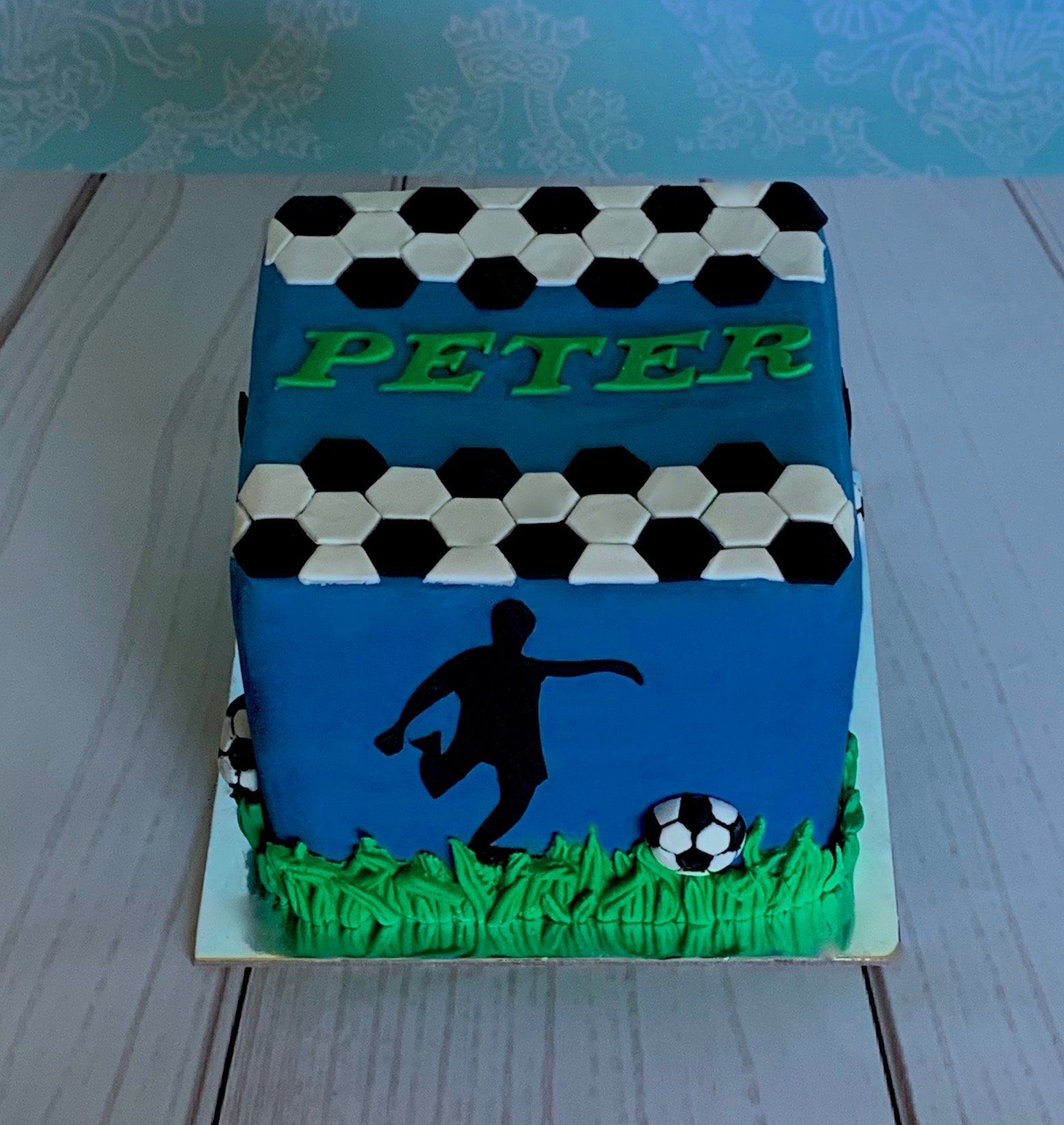 Soccer themed cake with black silhouettes, 3d moulded grass and soccer balls. Front