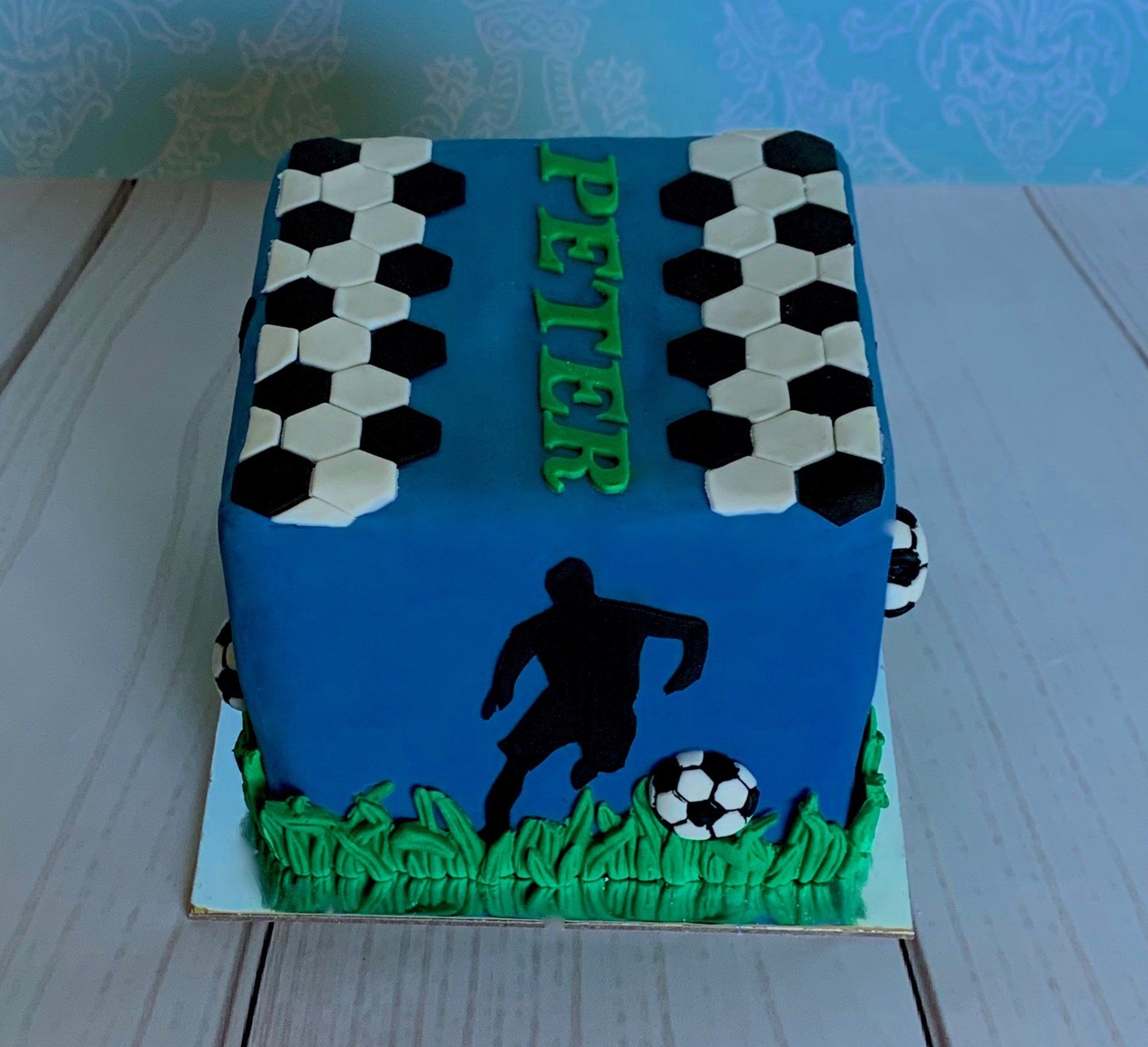 Soccer themed cake with black silhouettes, 3d moulded grass and soccer balls. Side 1