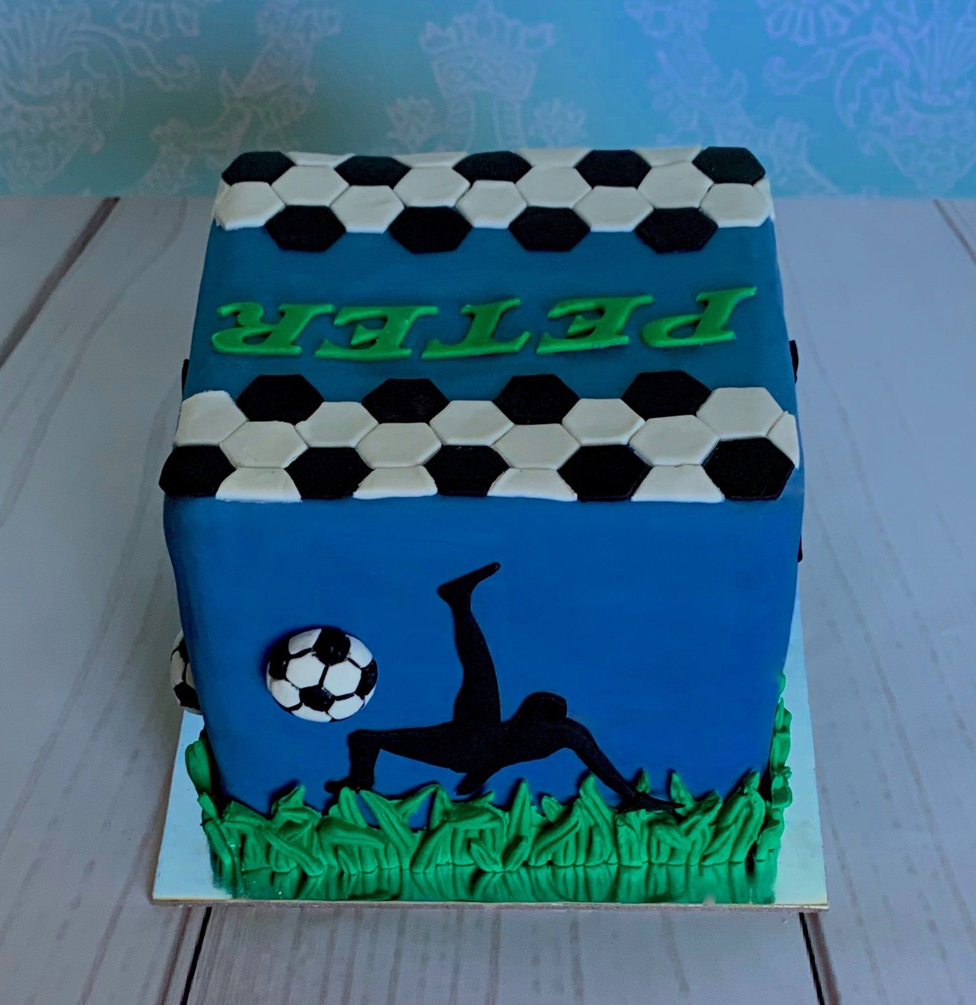 Soccer themed cake with black silhouettes, 3d moulded grass and soccer balls. Back.