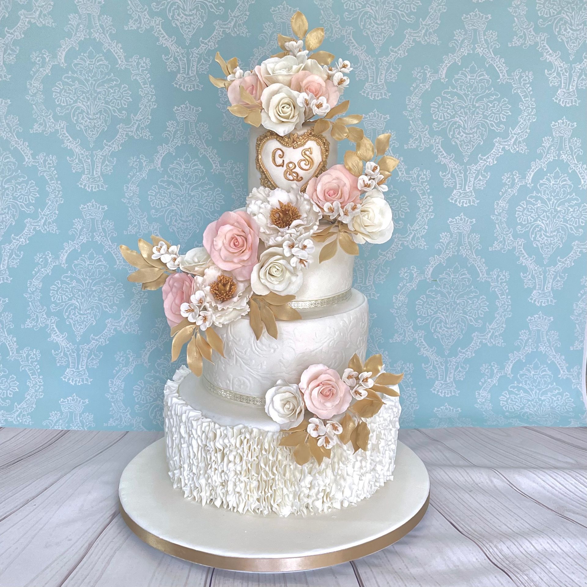 4 tier Wedding Cake Sails Resort Port Macquarie. White embossed and textured fondant tiers, Trimmed with Ribbon and Decorated with Handmade Sugar Flowers, Sugar leaves in white, Champagne gold and soft pink.