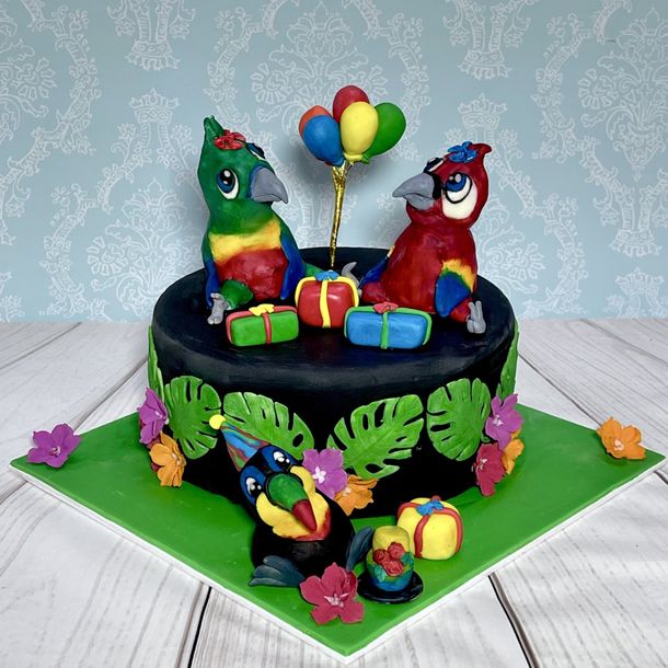 Super Cute Birthday Cake with two gorgeous hand sculpted parrots and a hand sculpted toucan having a party. Complete with fondant presents, balloons, leaves and flowers.