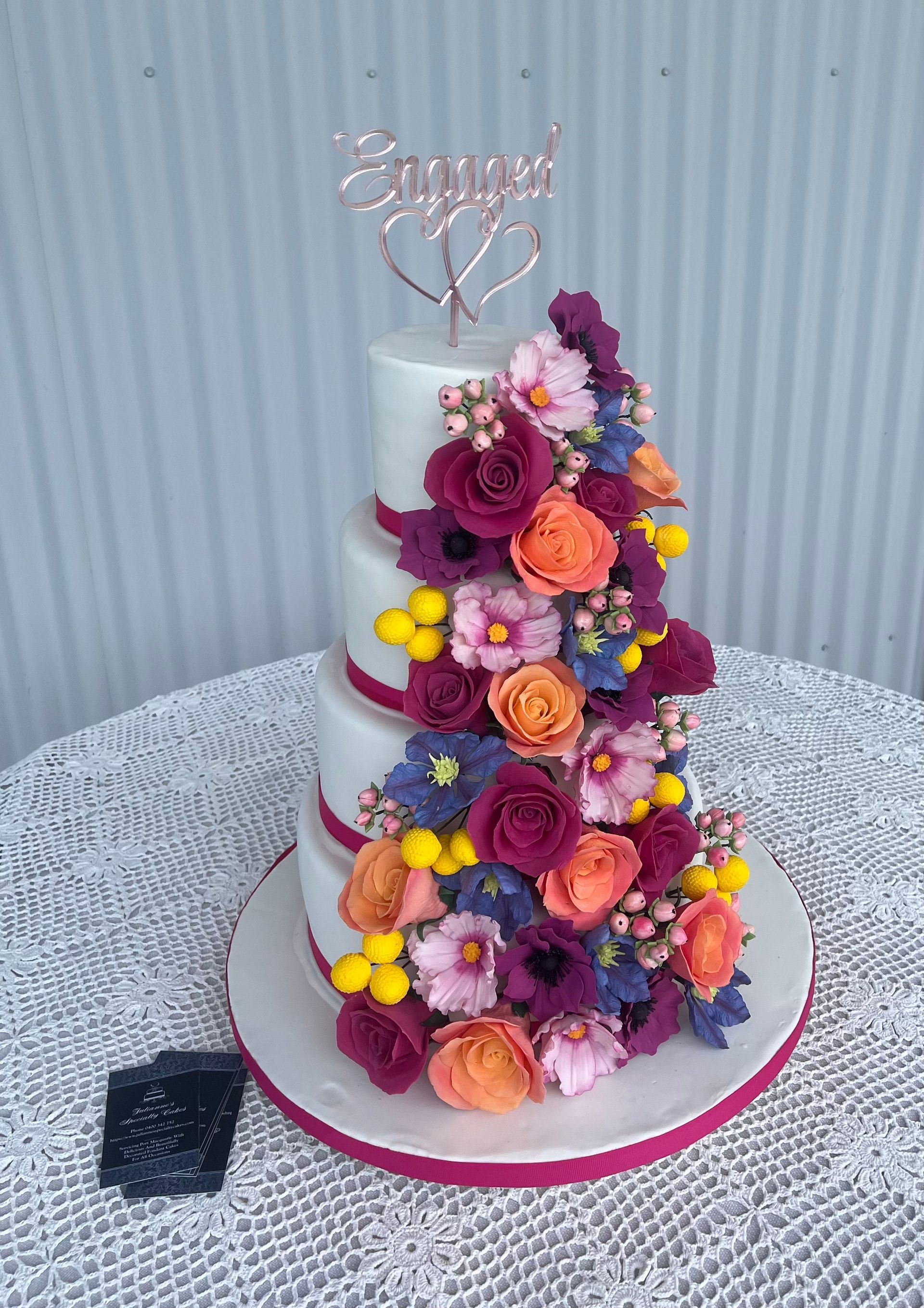 Gorgeous neutal Baby Shower Cake. White fondant with a blue, pink, aqua, mauve and white crochet effect around the sides, Fondant crocheted rug on the top, with a cute hand sculped fondant baby bear holding a bottle, and surrounded by moulded fondant baby toys.