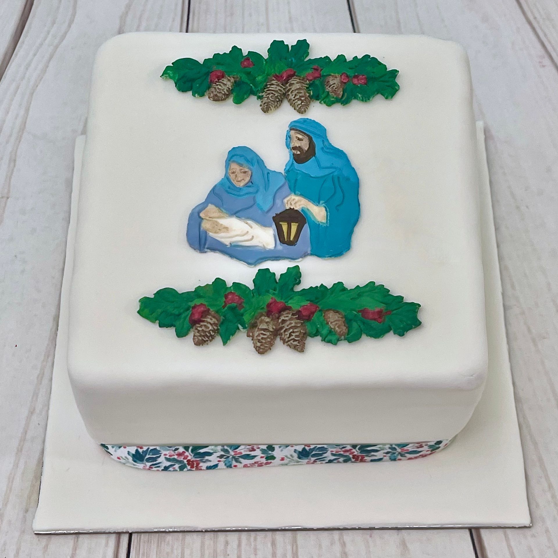 Christmas Cake with nativity holly and pine cone decorations. 