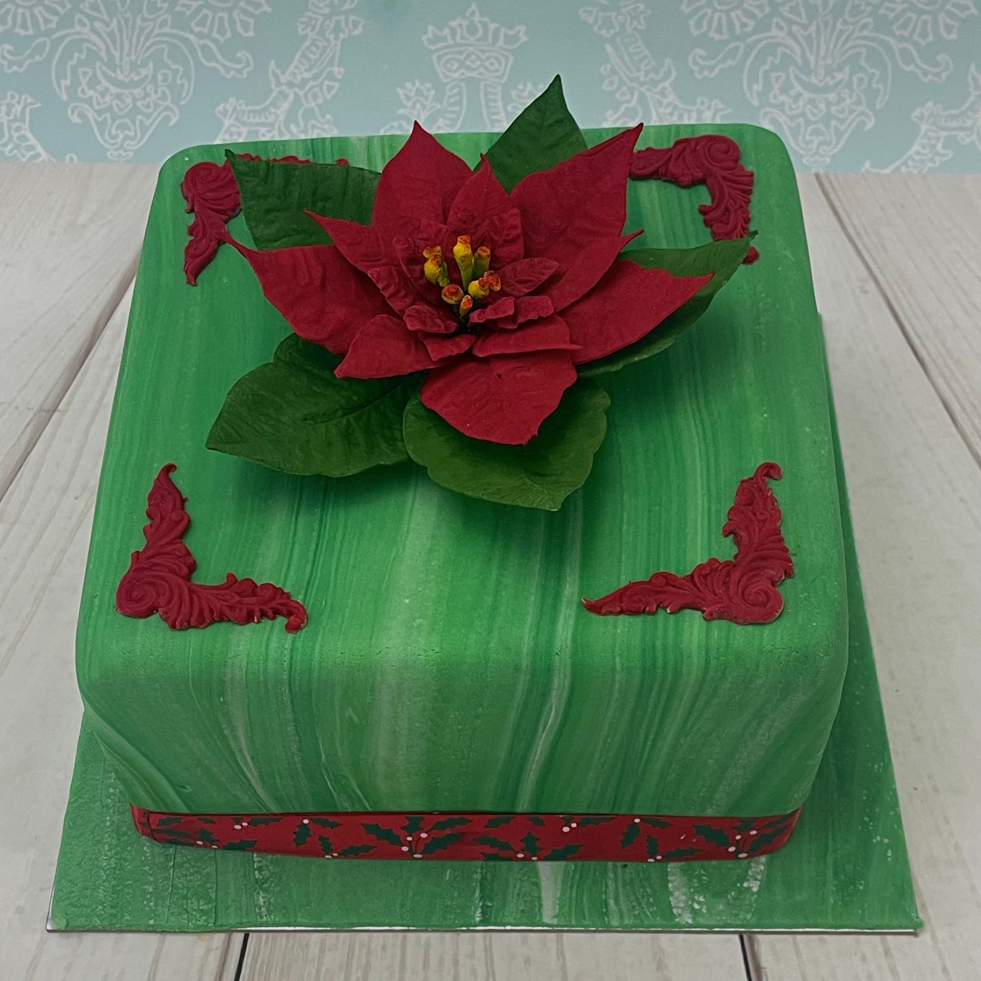 Christmas cake with green marbled fondant and a handmade sugar poinsettia. 