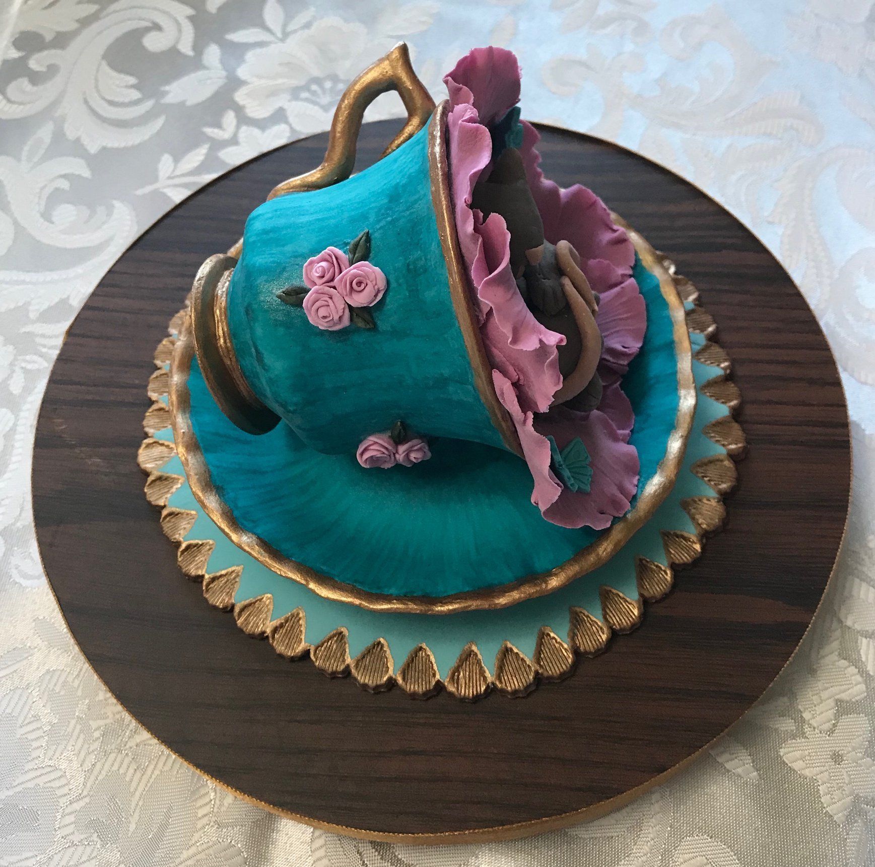 Cake topper of two very cute mice sleeping in a flower inside an ornate teacup.