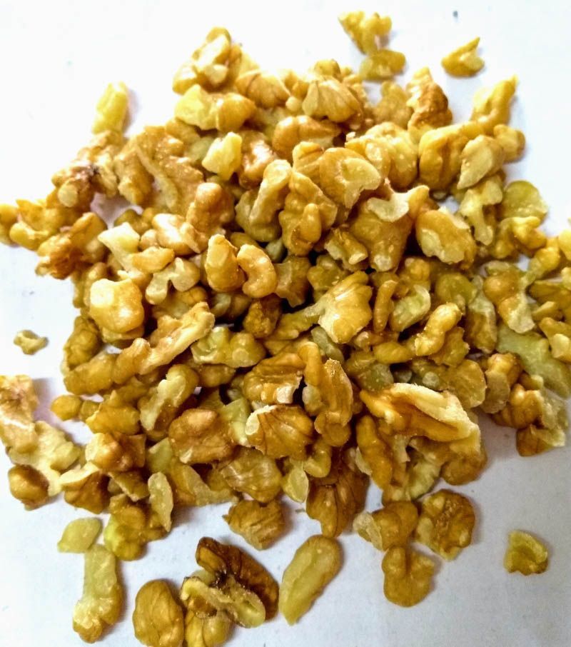 Un montón de mitades de nueces de color marrón dorado sobre una superficie blanca.