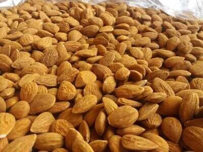 Montón de almendras que llena el marco, nueces de color marrón dorado apiladas densamente.