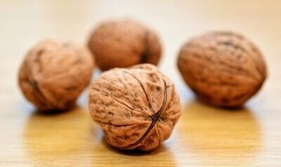Cuatro nueces sobre una superficie de madera, una de ellas enfocada nítidamente en primer plano.