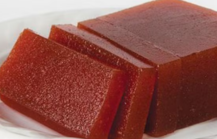 Rebanadas de pasta o gelatina de fruta roja brillante apiladas en un plato blanco.