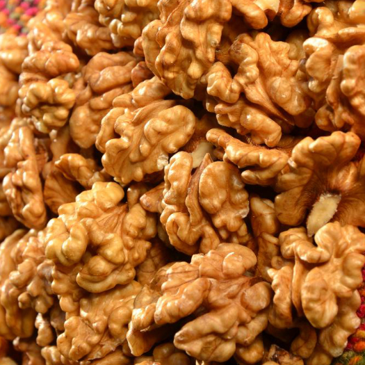 Primer plano de un montón de mitades y trozos de nuez de color marrón dorado.