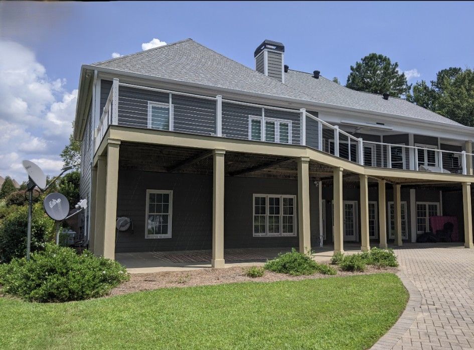 Two-story house with a gray exterior, a deck, and green lawn. Blue sky in the background.