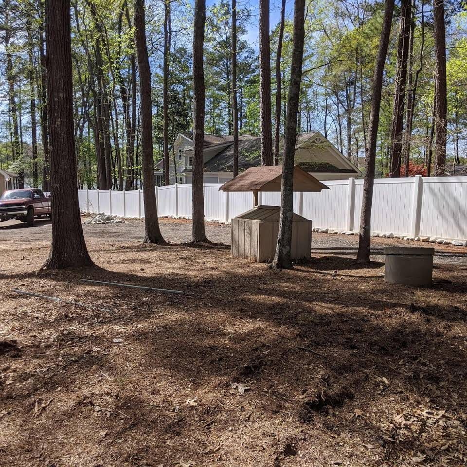 A white fence is surrounded by trees in a park.